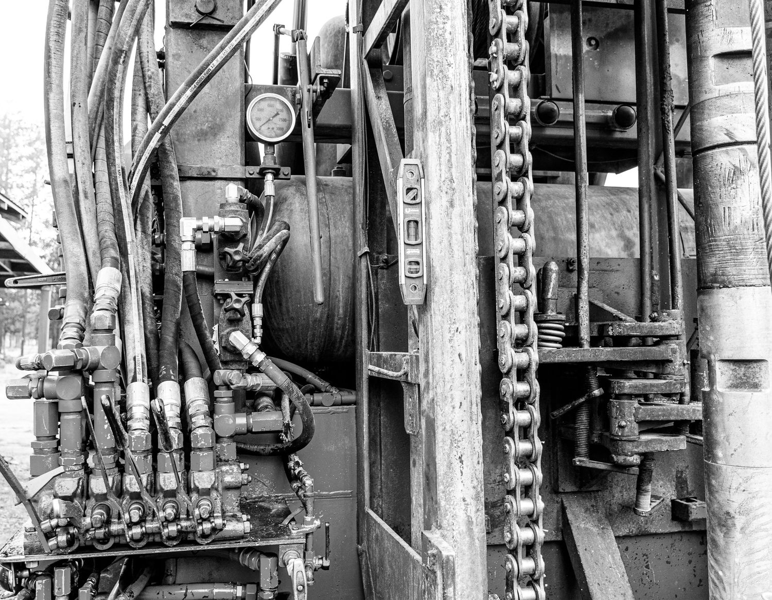 Detailed view of industrial machinery with pipes, gauges and chain mechanisms.