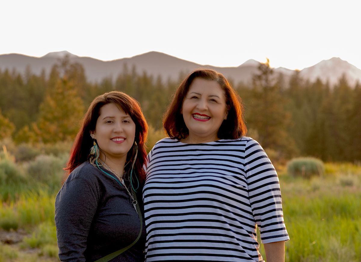 A casual group photo taken outdoors with mountains and natural scenery in the background.