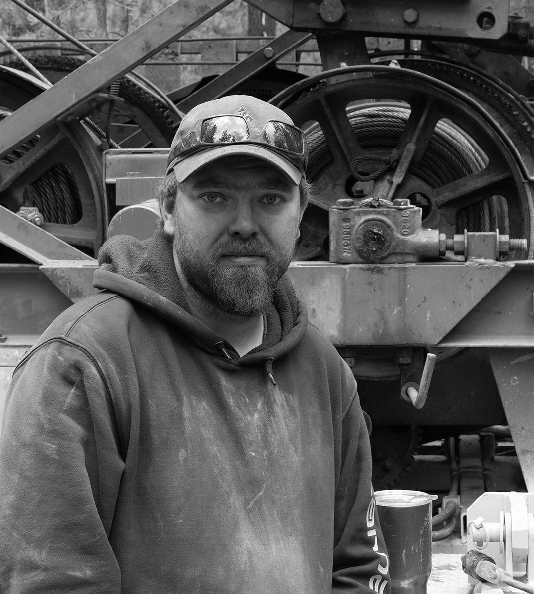 Worker standing in front of vintage industrial machinery in black and white.