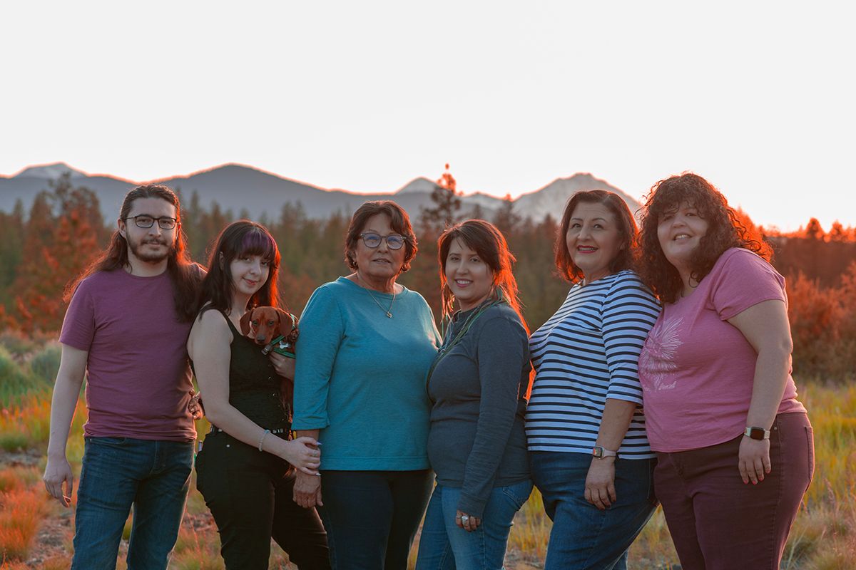 Family posing together at sunset with mountains visible in background.