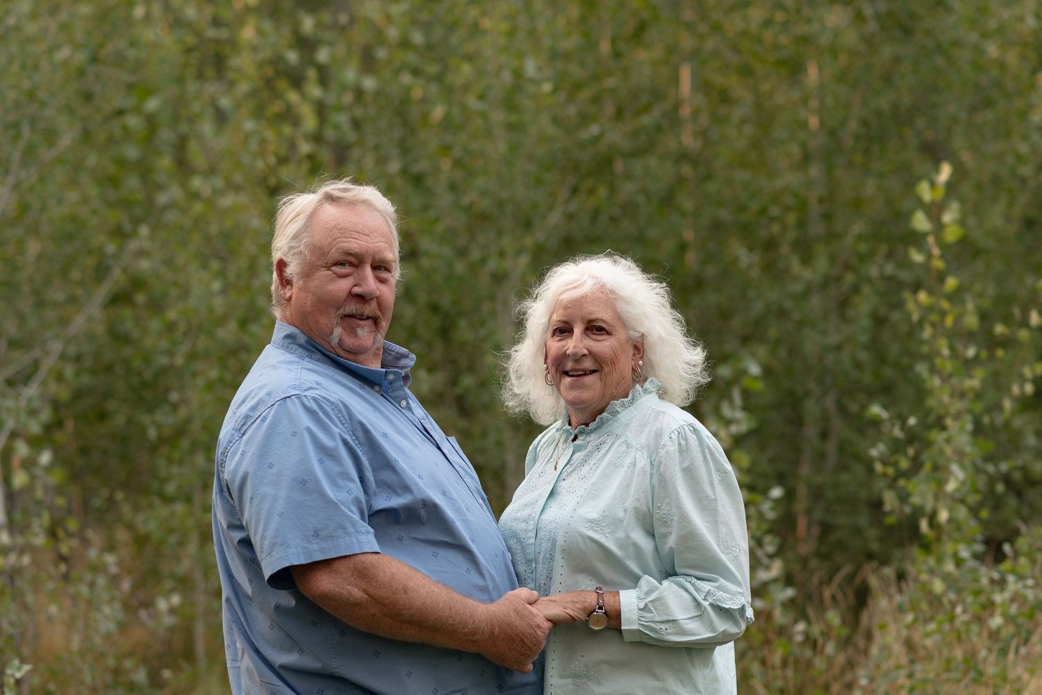 Couple enjoying a romantic moment together in an outdoor garden setting with greenery in the background.