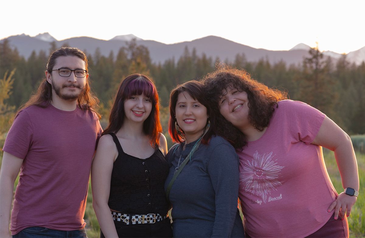Family gathered together wearing casual attire against a mountainous backdrop at sunset.