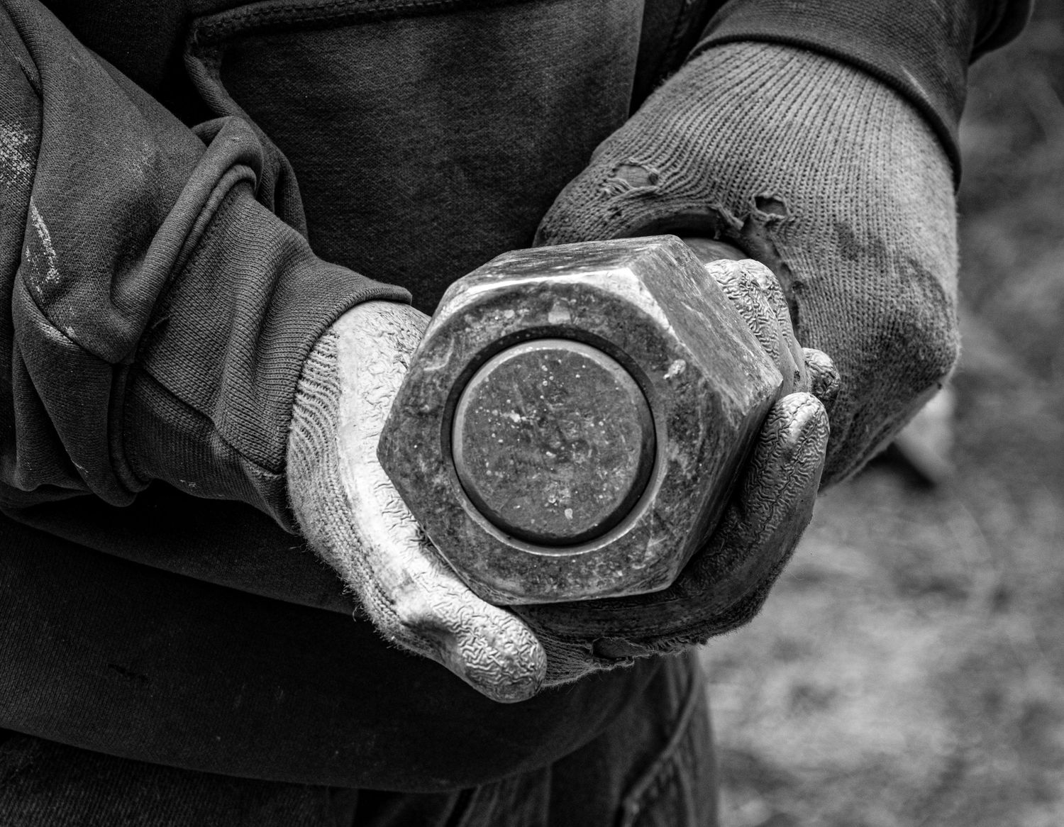 Black and white image of dirty gloved hands holding an old compass.