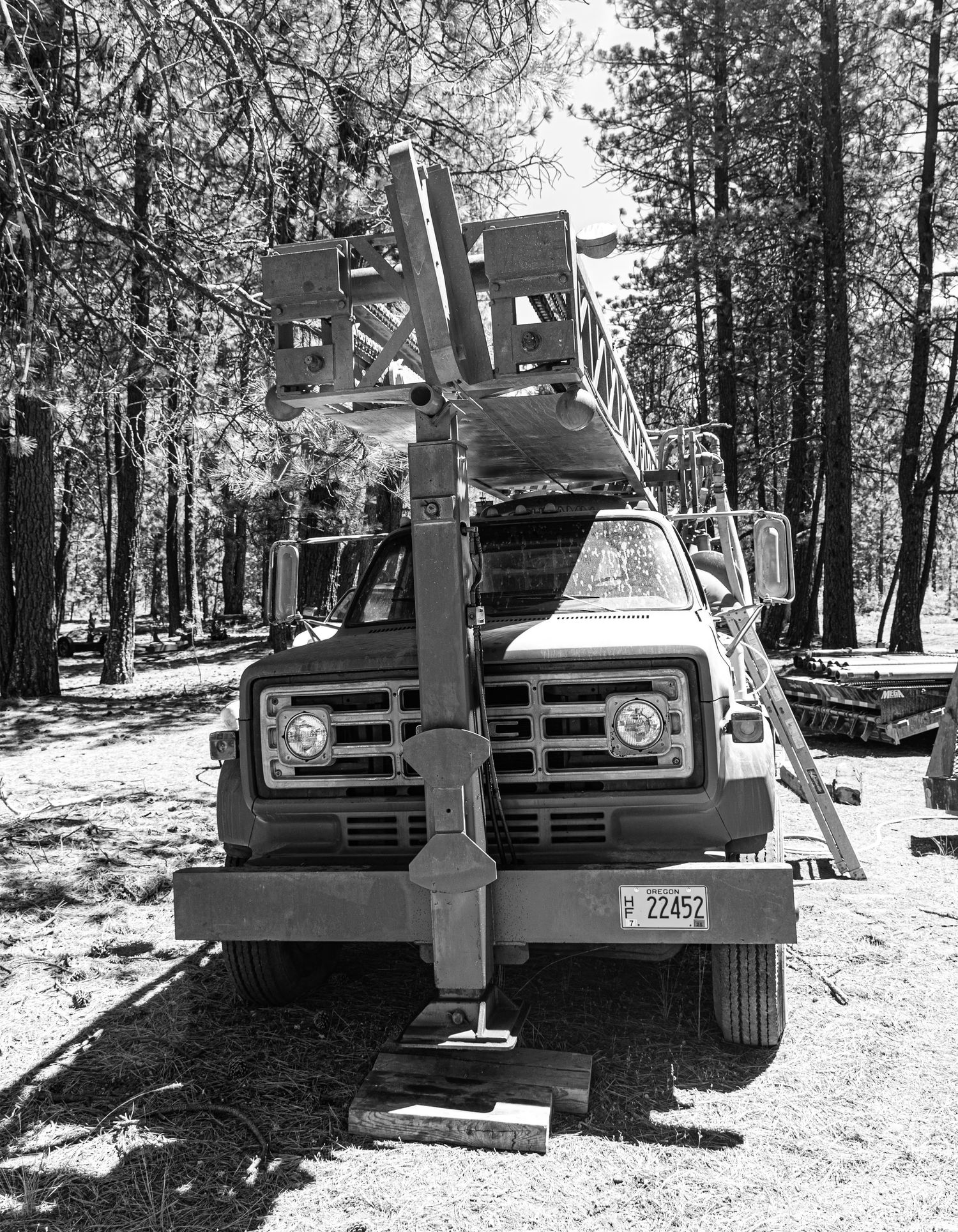 Heavy-duty work truck with mounted crane equipment parked in a forested area.