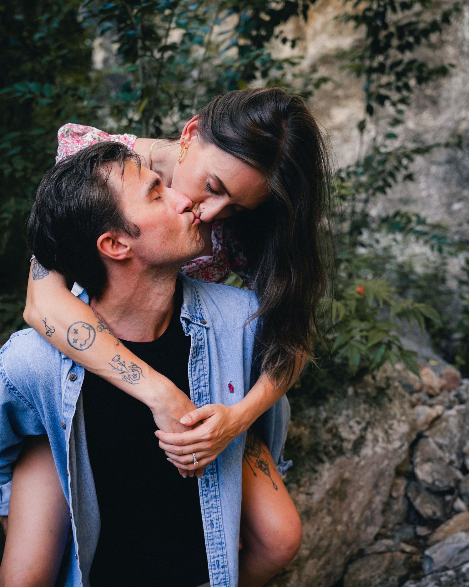Romantic couple shares intimate moments in a natural outdoor setting with rock formations and greenery in the background.