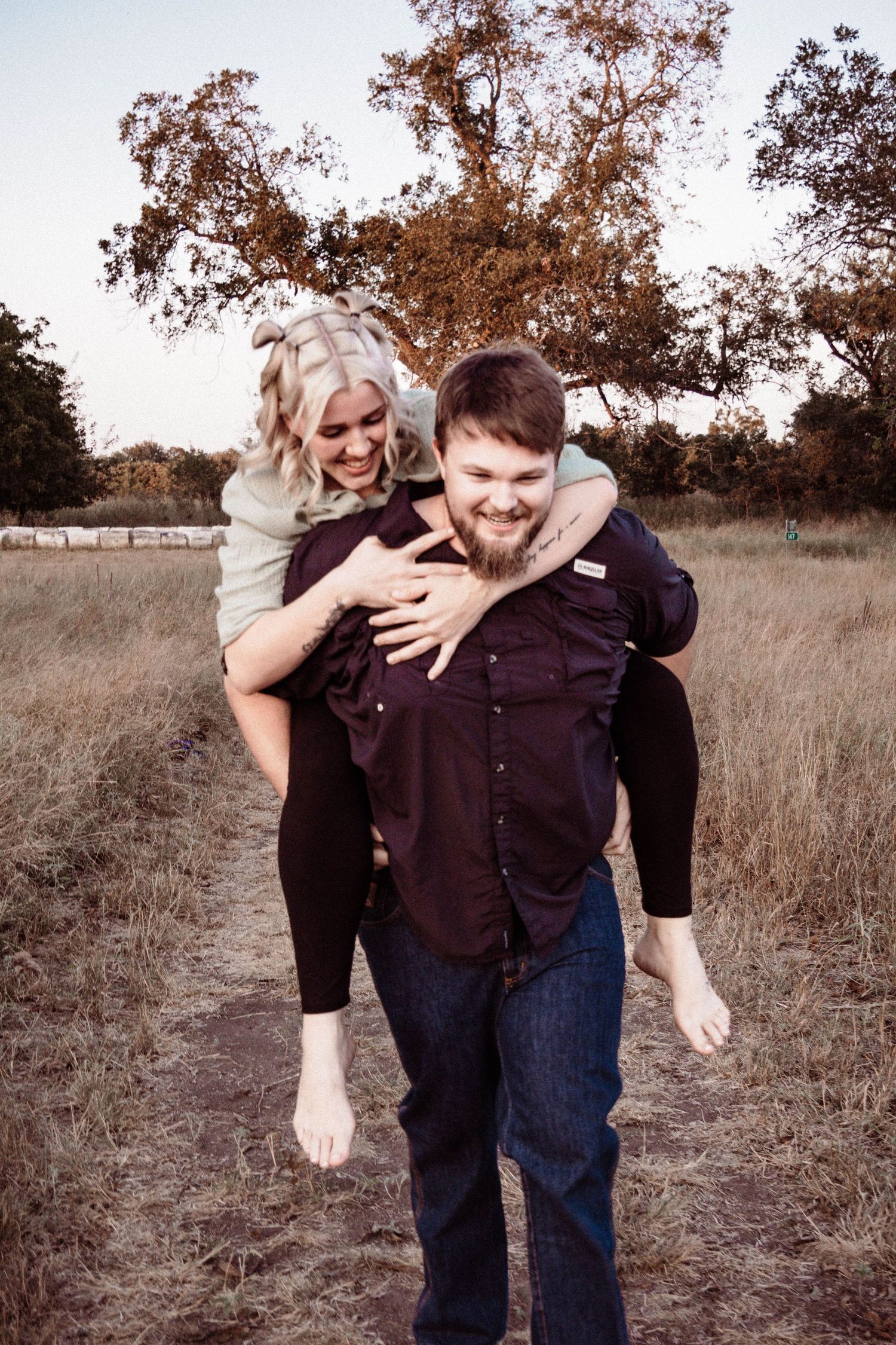 A playful piggyback ride moment captured in a rustic field during golden hour.