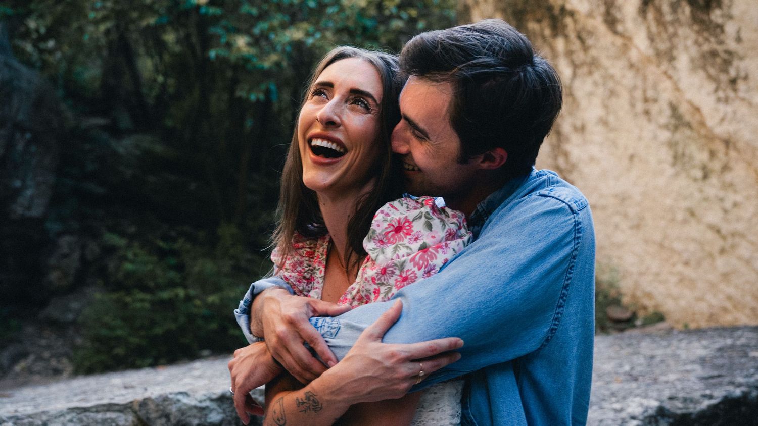 Happy couple embraces while laughing and enjoying romantic moments together outdoors near rocky cliffs.