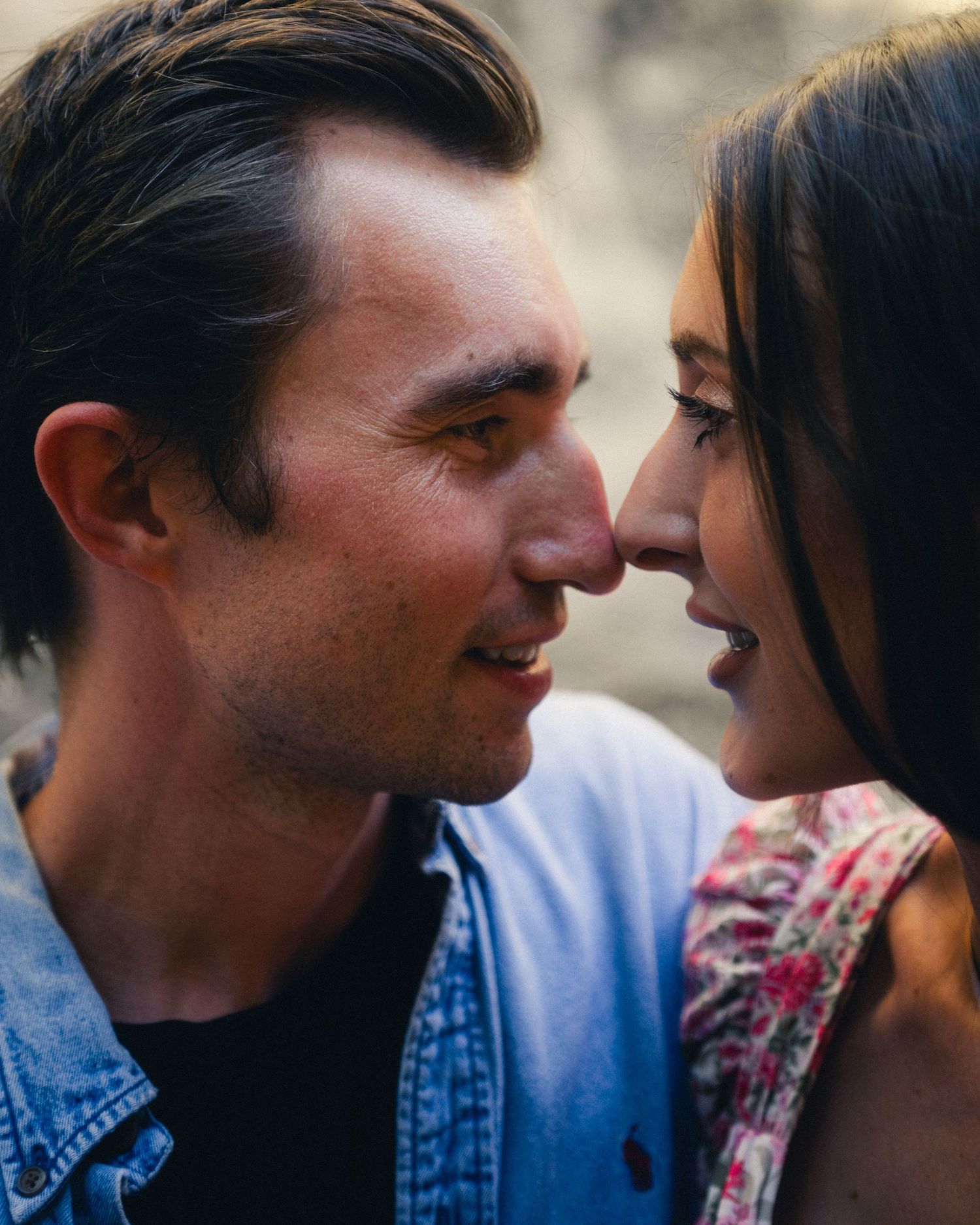 A couple draws close to each other in an intimate moment wearing denim and floral clothing.