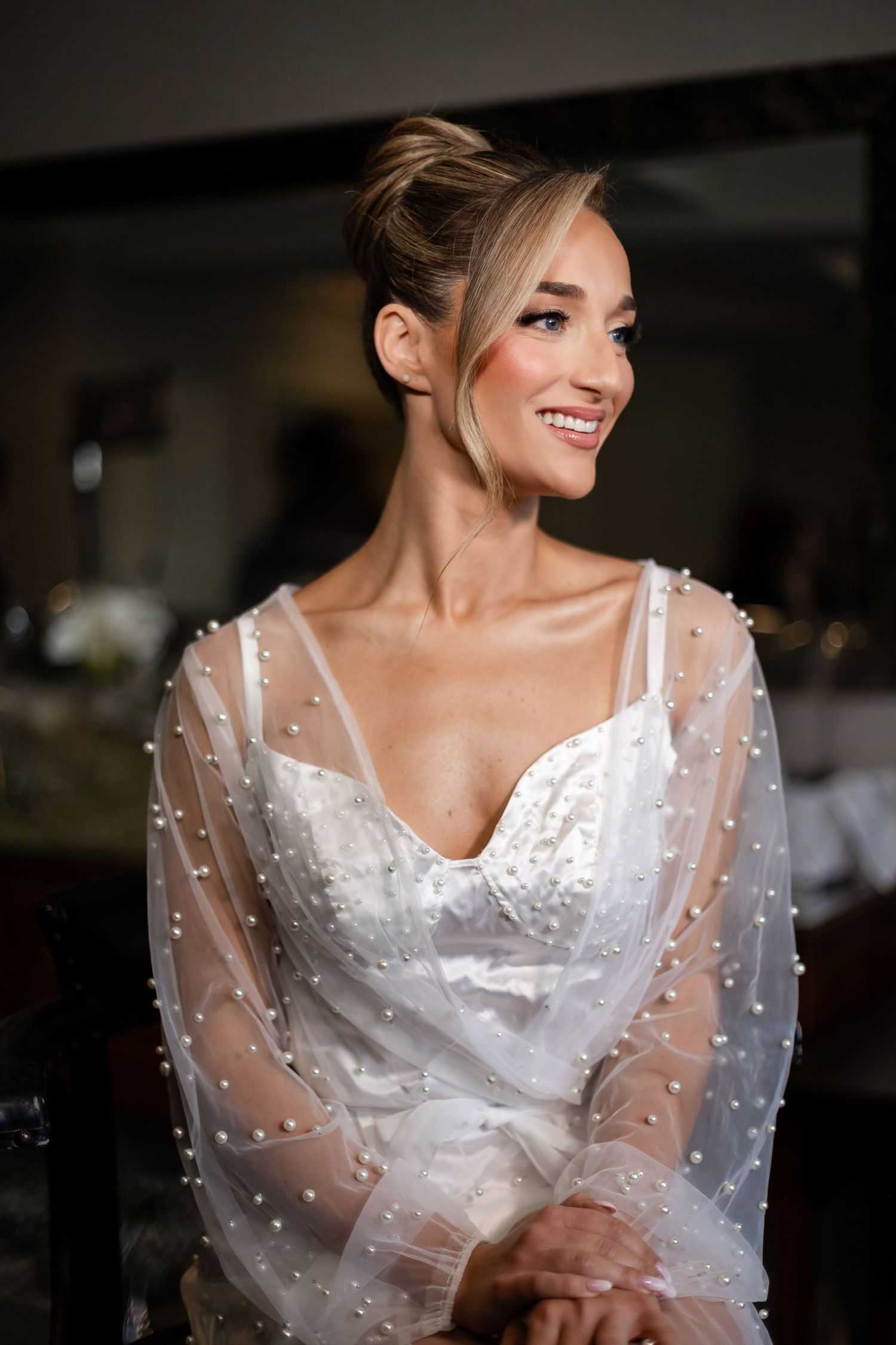 Bride in a white wedding dress with sheer polka dot sleeves smiles elegantly in a series of candid poses.