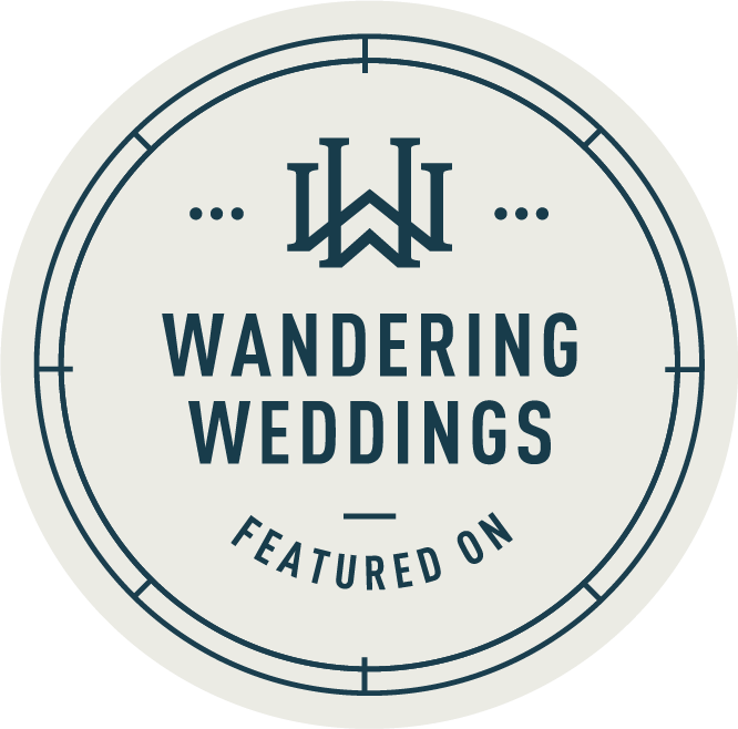 Circular blue and white logo for Wandering Weddings featuring website.