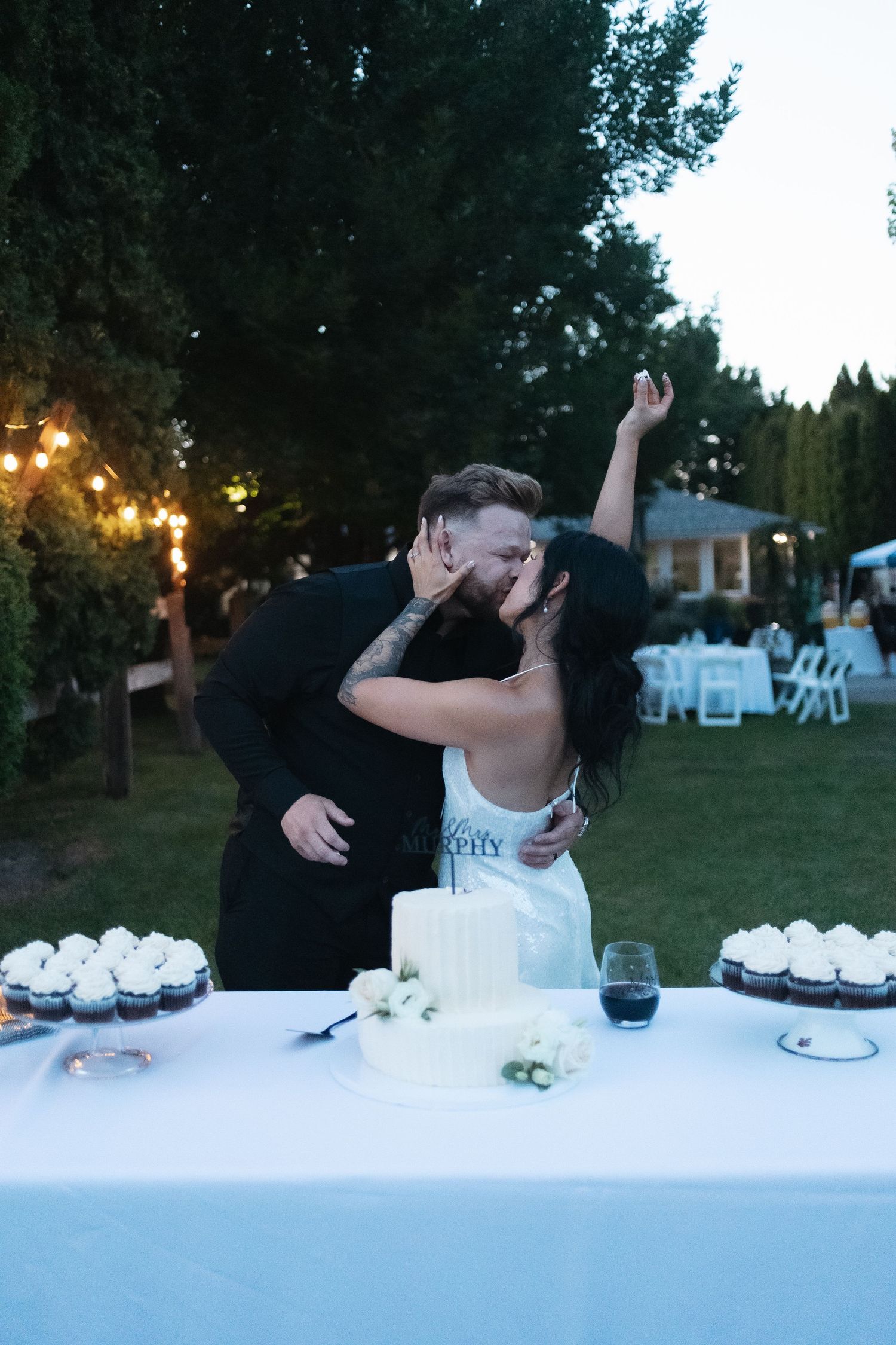 A couple shares a celebratory dance moment at an outdoor reception table.