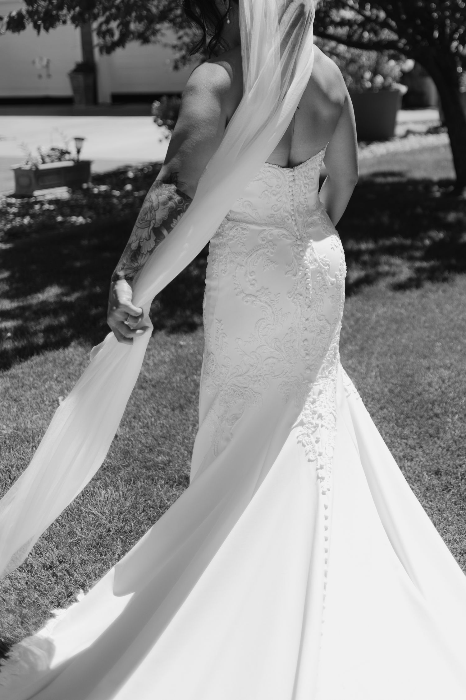 Black and white close-up detail shots of a white lace wedding dress with flowing fabric and delicate embellishments.