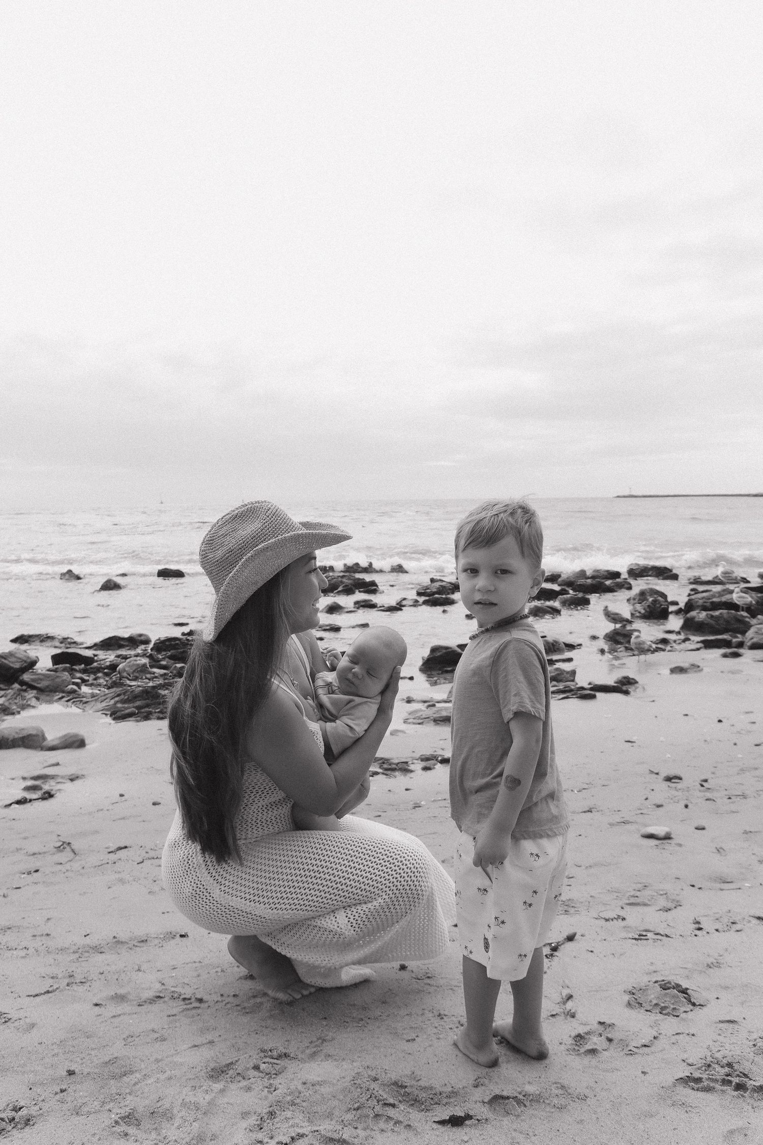 Black and white photo series showing tender moments between parent and child playing together on a rocky beach.