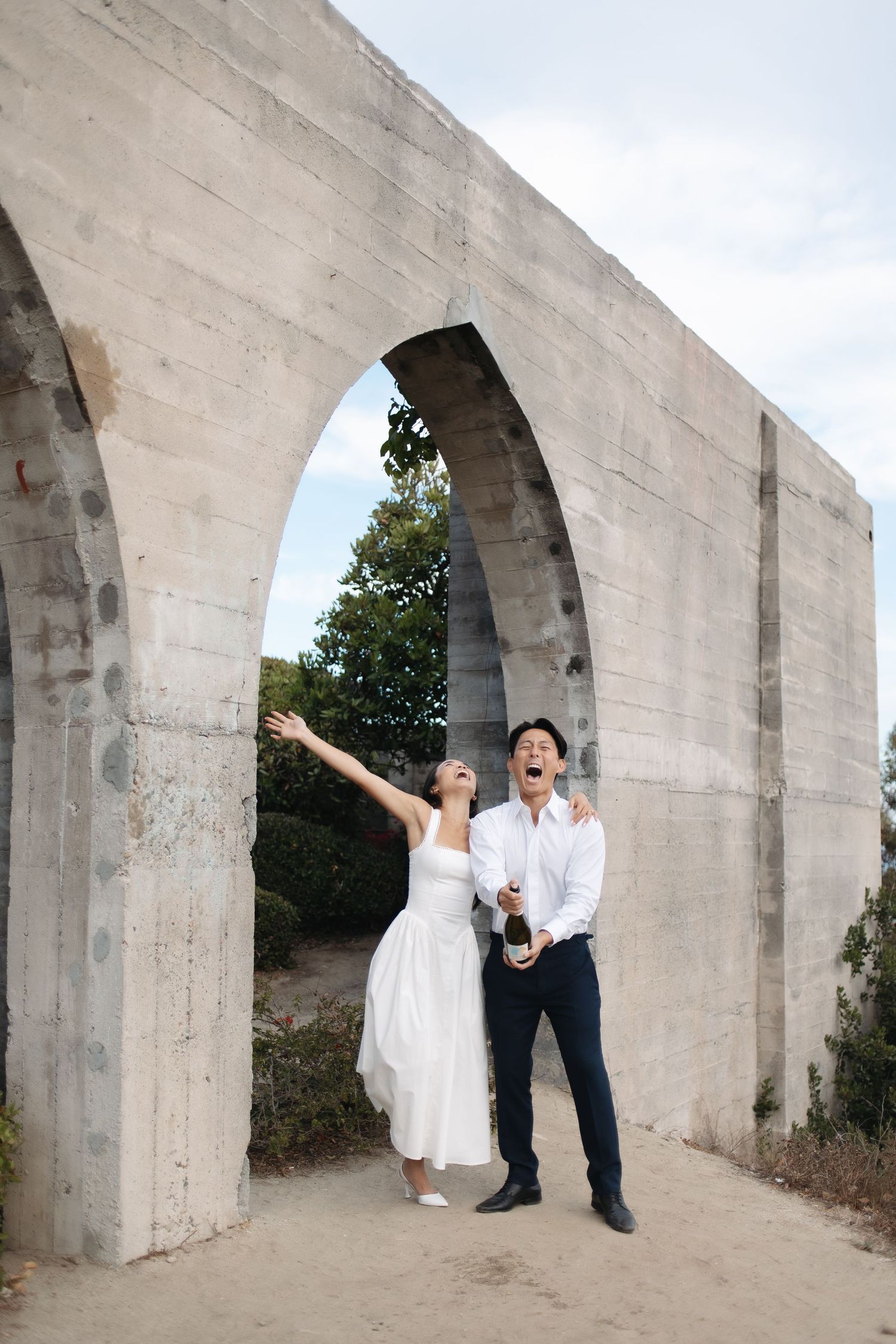 A couple in wedding attire playfully poses in a sequence of photos under concrete archways outdoors.