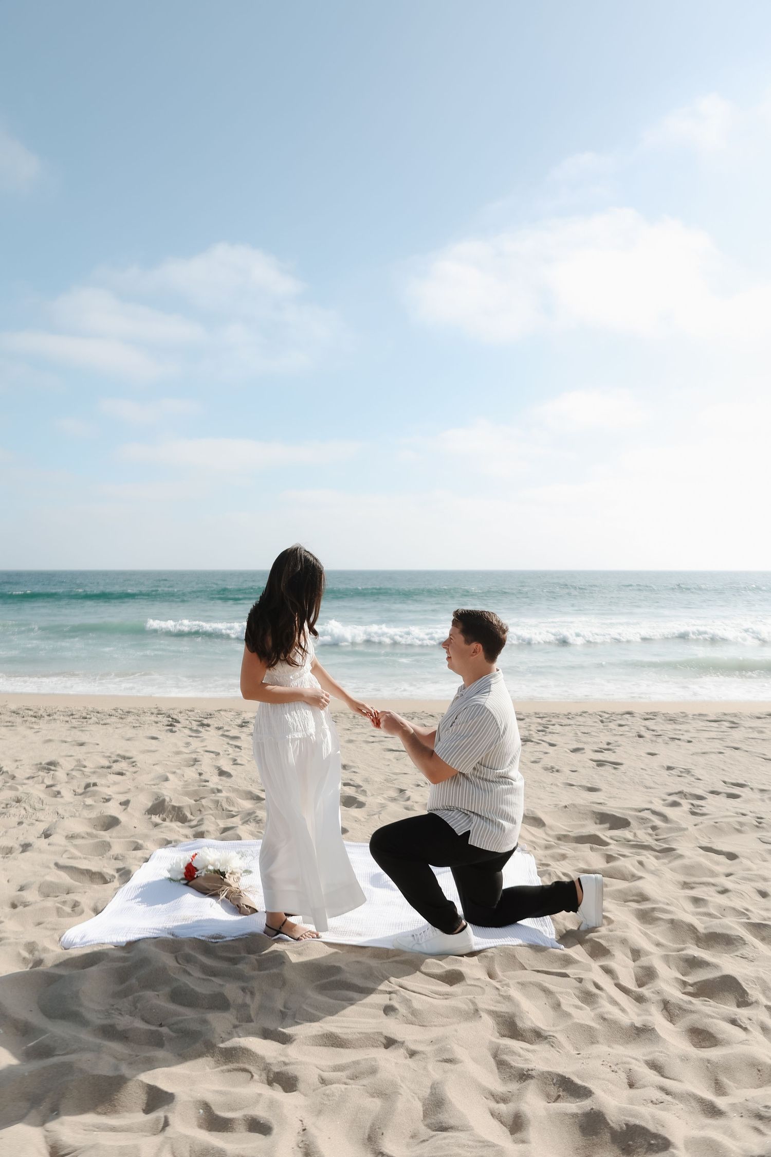 Couple sitting on beach sand enjoying a peaceful moment by the ocean.