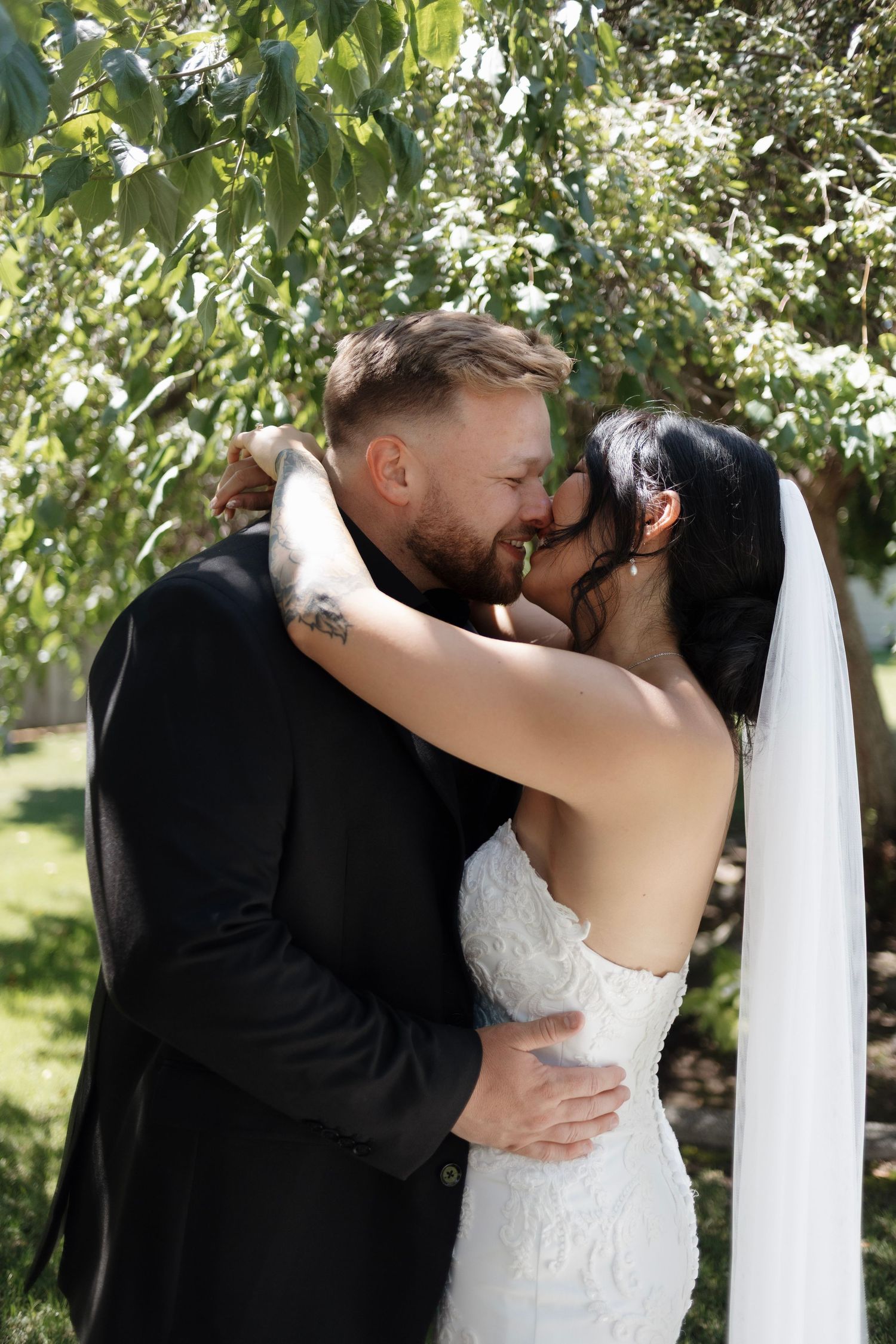 A romantic sequence of wedding photos showing a couple sharing their first kiss as newlyweds in a sunlit garden setting.