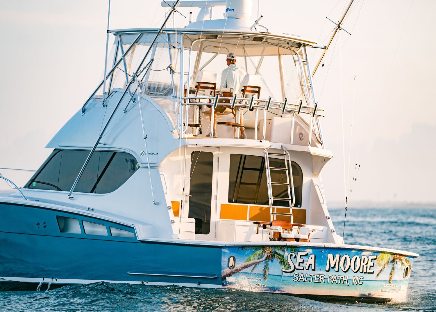 White sport fishing yacht named Sea Moore navigates open water during a blue marlin fishing tournament at sunset.