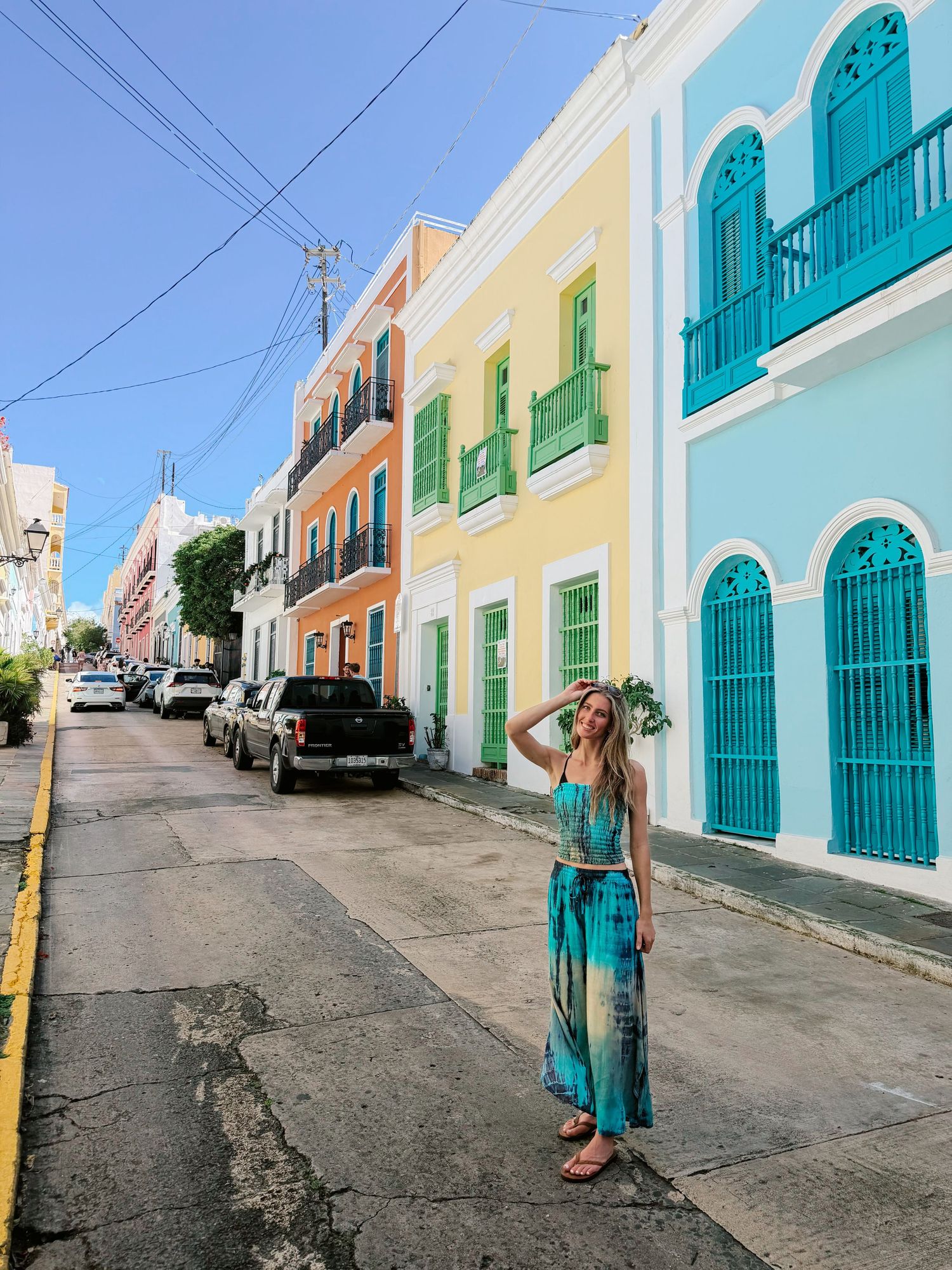 Woman in turquoise maxi dress posing on colorful colonial street in Old San Juan Puerto Rico.