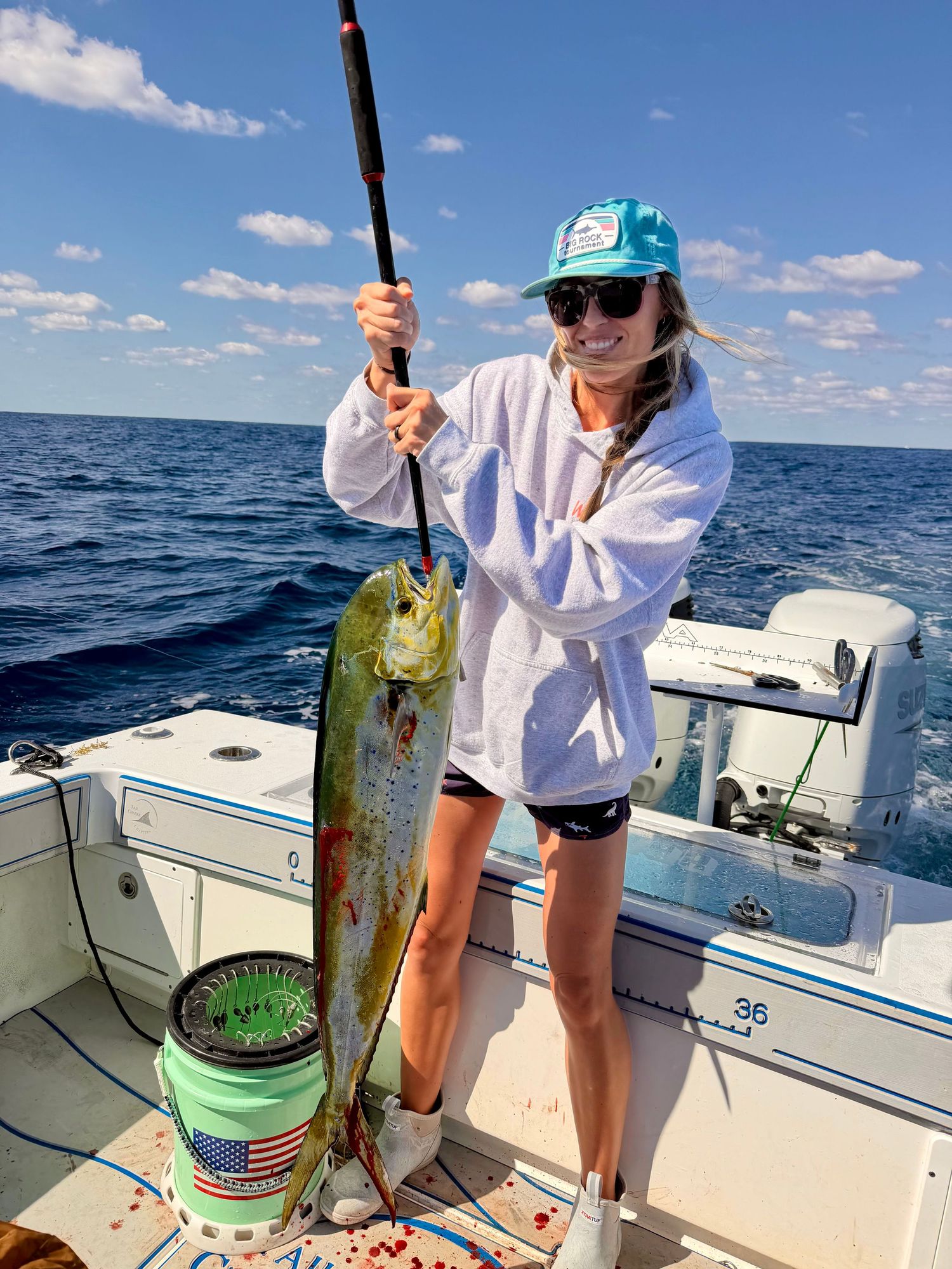 Smiling woman holding large mahi-mahi fish on deep sea fishing boat.
