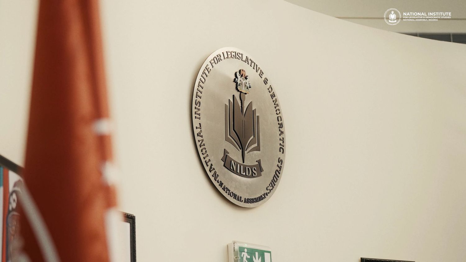A row of silver medallions and plaques mounted on a brown wall display various awards and achievements.