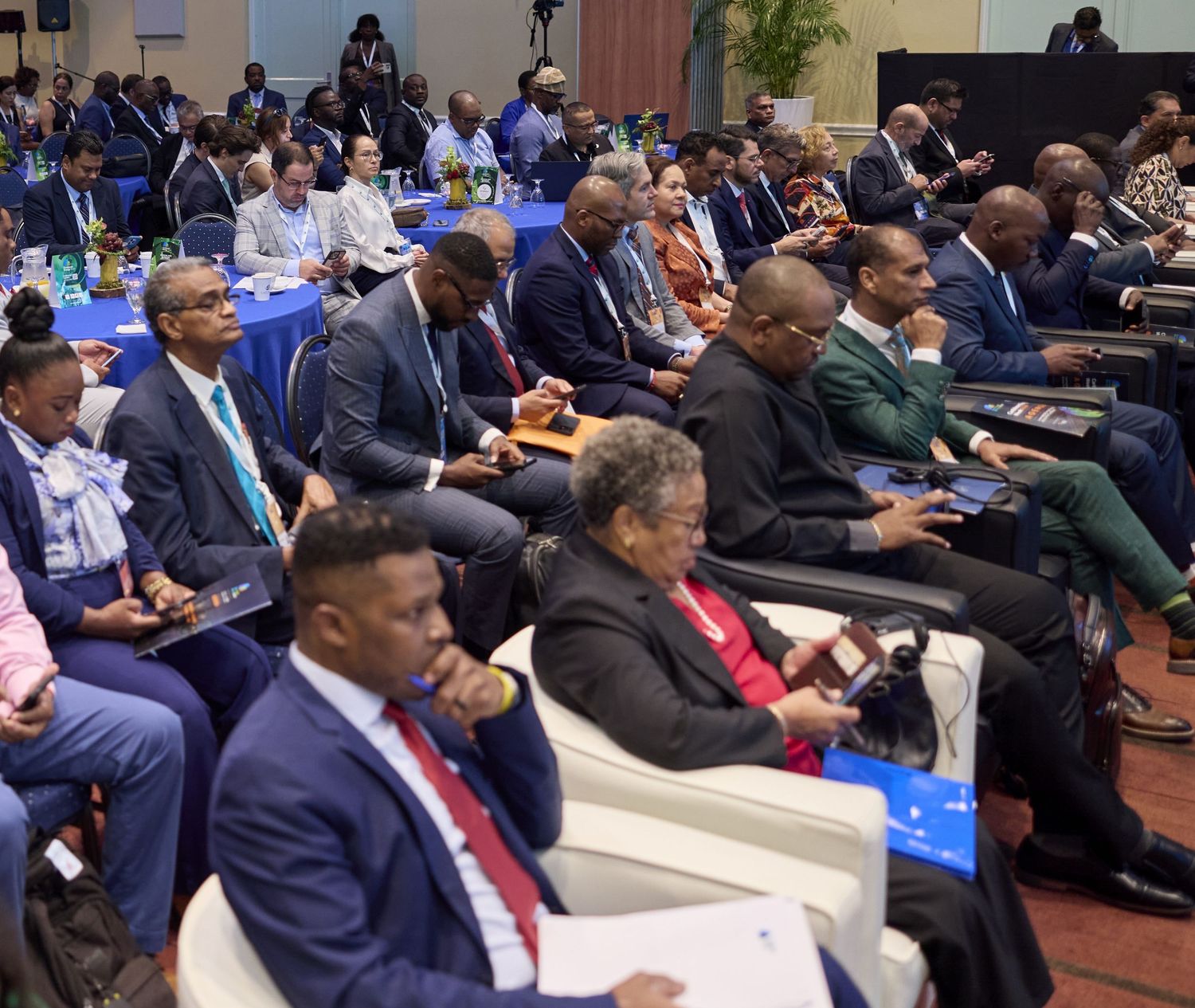 A large audience of professionals in formal attire seated at a conference hall during an international business summit.