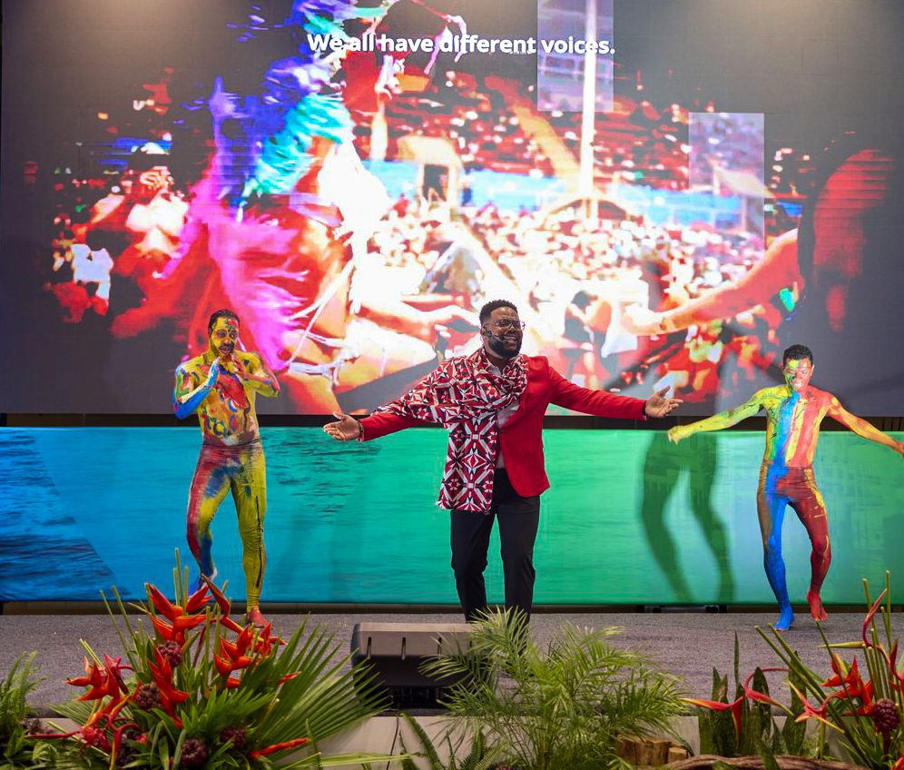 Colorful performers dance on stage at Caribbean Energy Week event with vibrant backdrop.