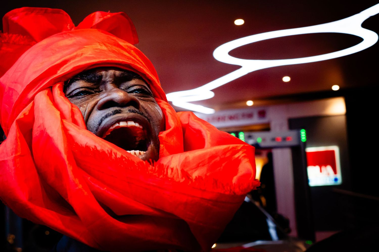 A series of four close-up photos bathed in red light show someone laughing and smiling expressively.