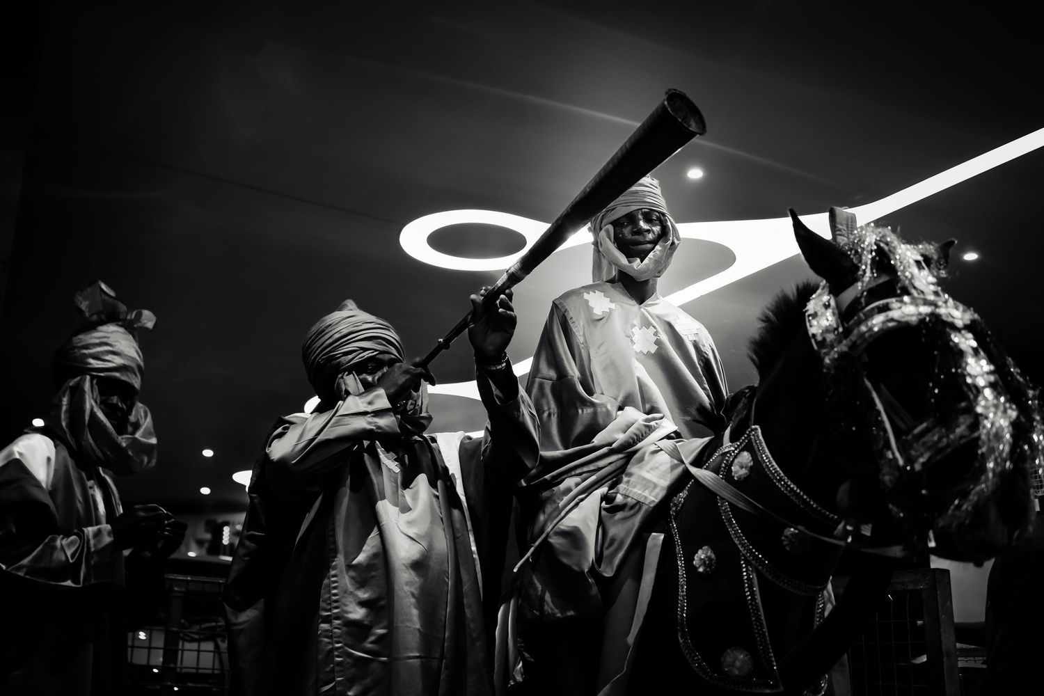 Black and white panoramic shot of performers in silhouette on stage.