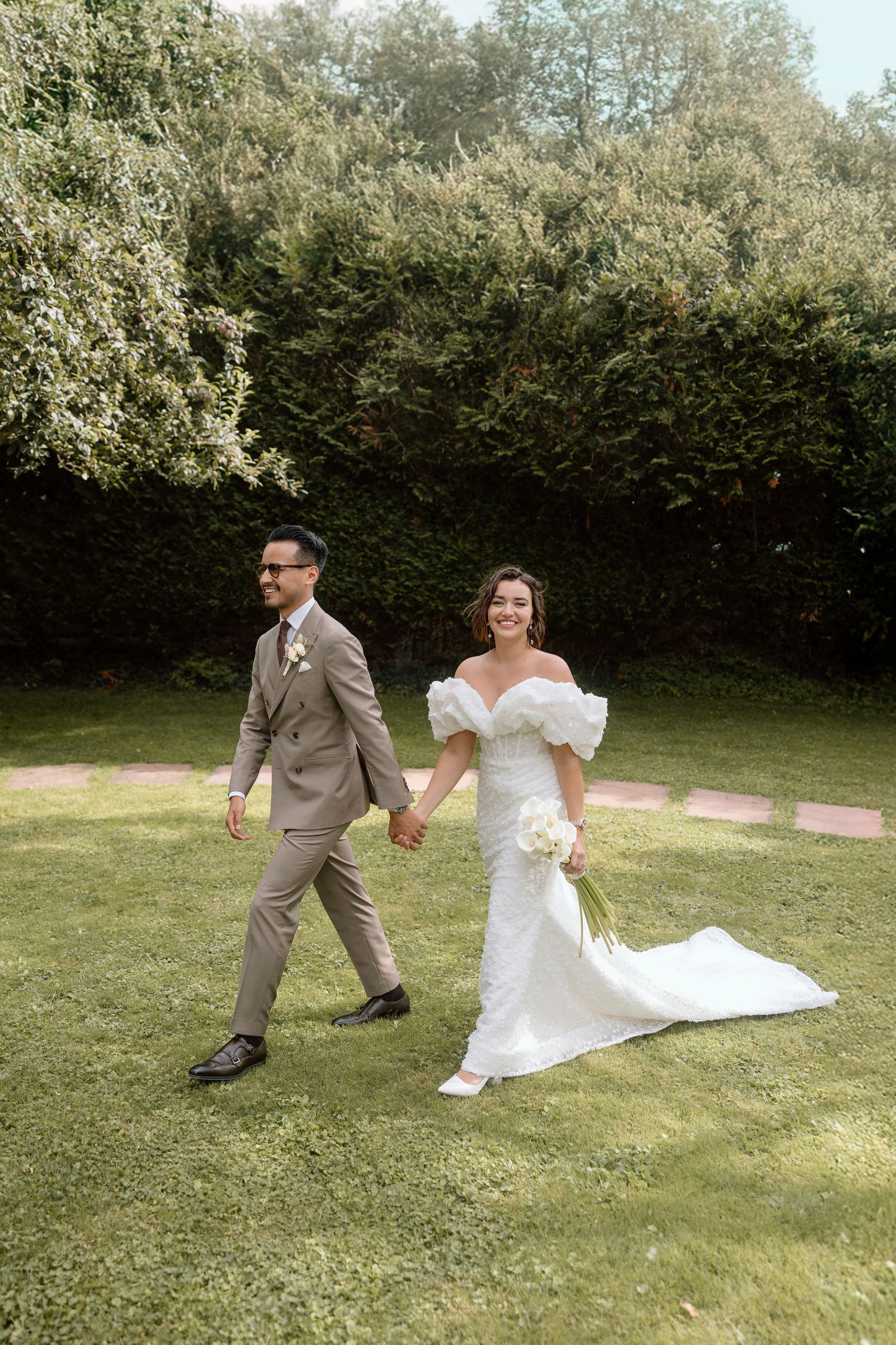 A couple frolics playfully on a grassy lawn during their wedding photoshoot.