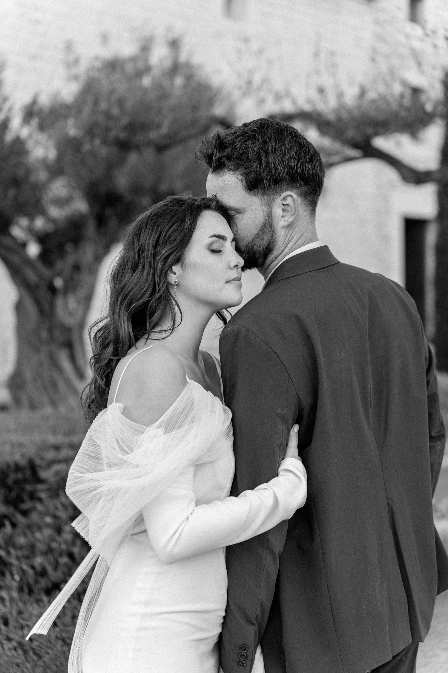 Black and white portrait of newlyweds in an intimate embrace outdoors.