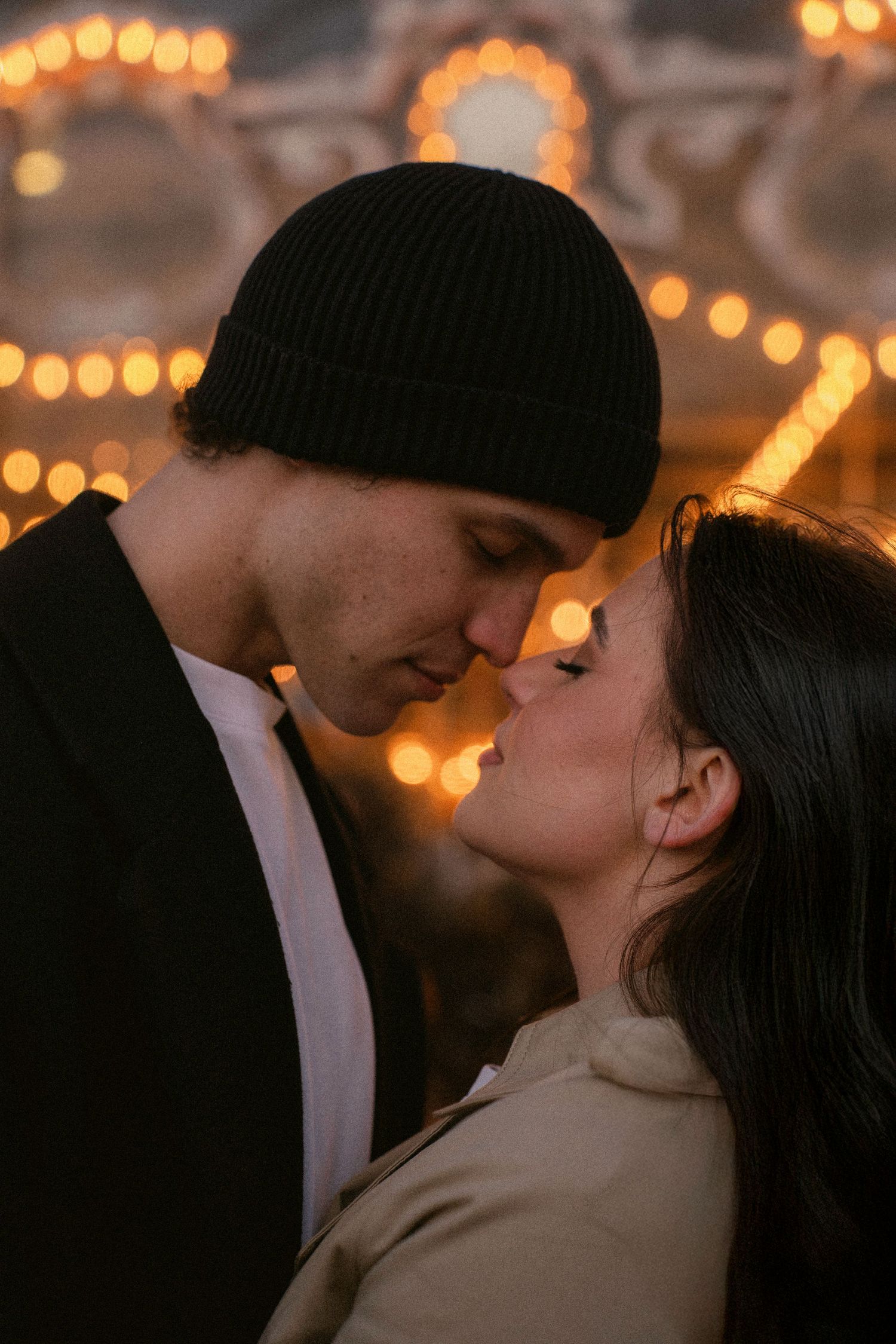 Romantic couple sharing intimate moment under warm string lights.