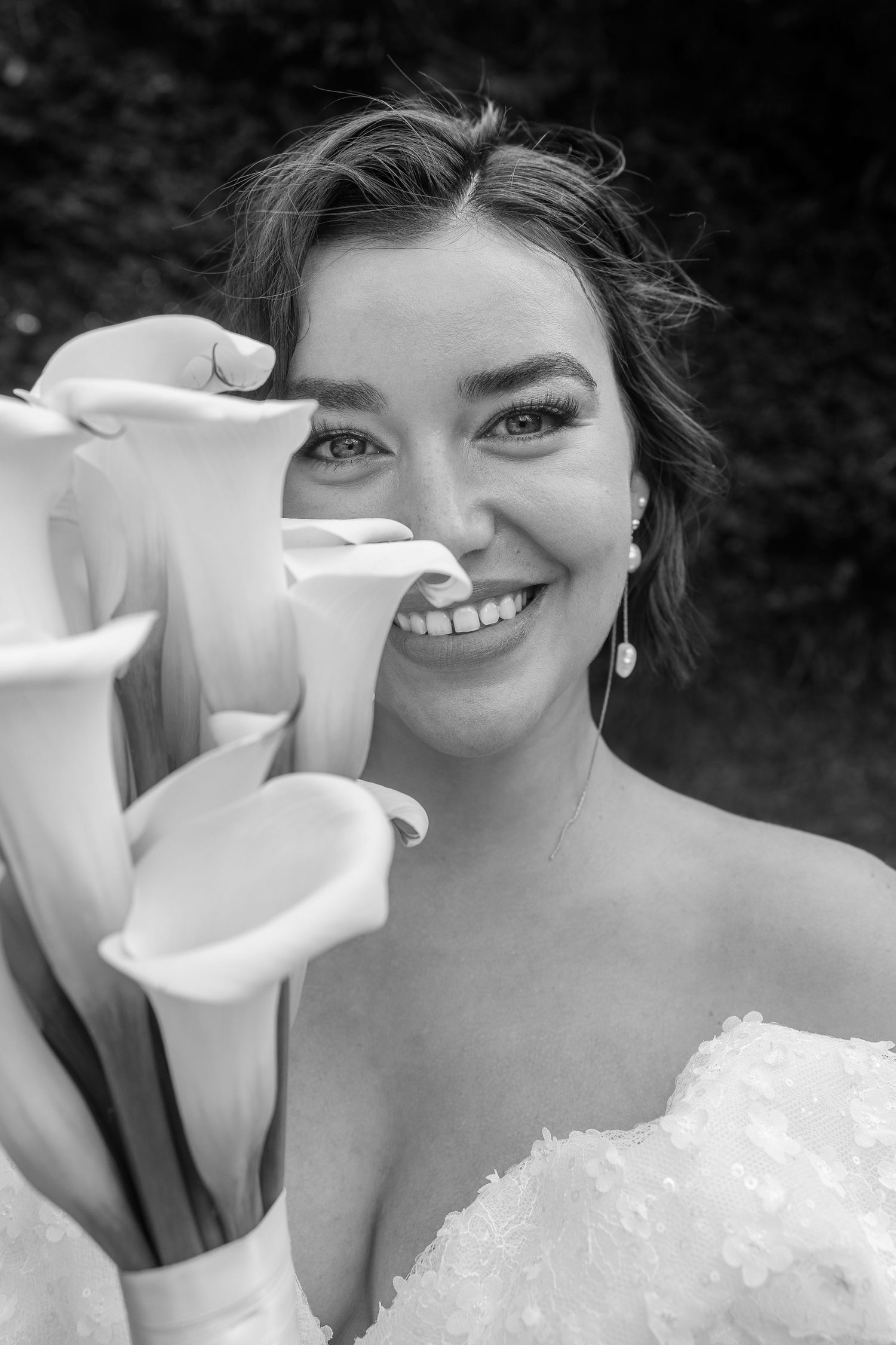 Close-up of white calla lily bouquet with bride in white dress.