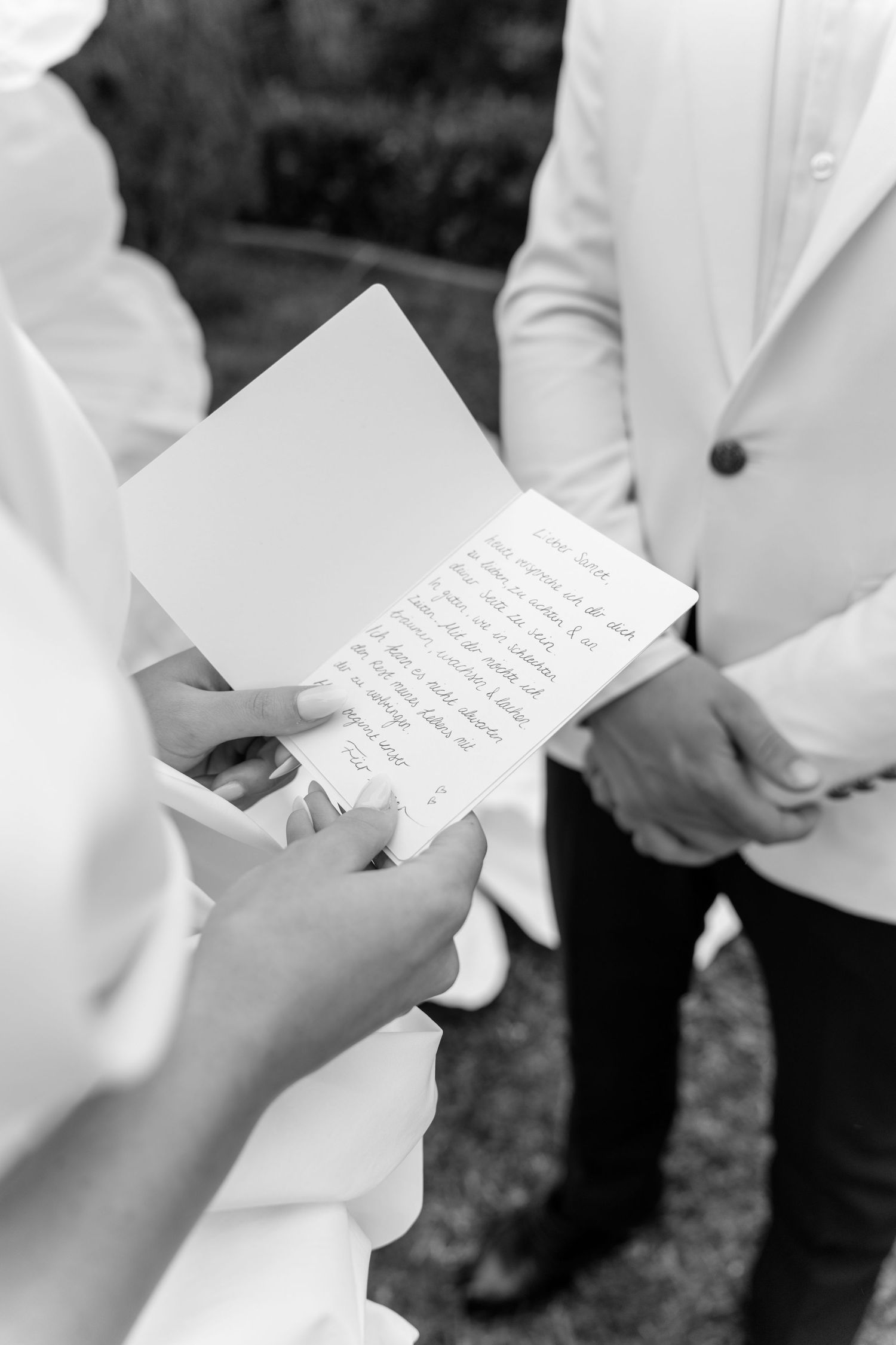 Close-up shots of hands holding handwritten notes in white formal attire.