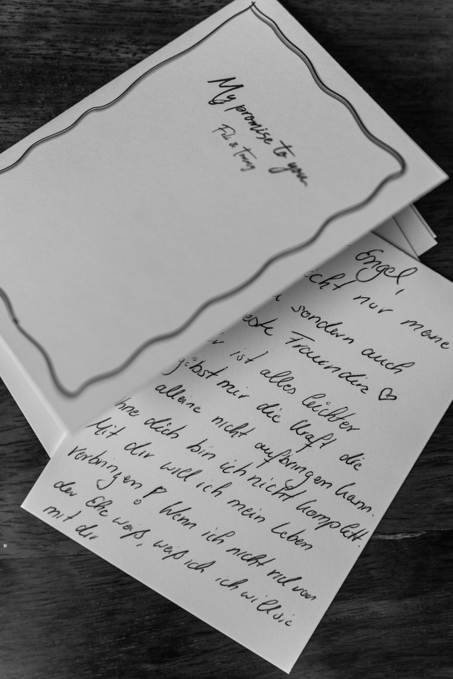 Handwritten letter with elegant script laid on dark wooden surface.