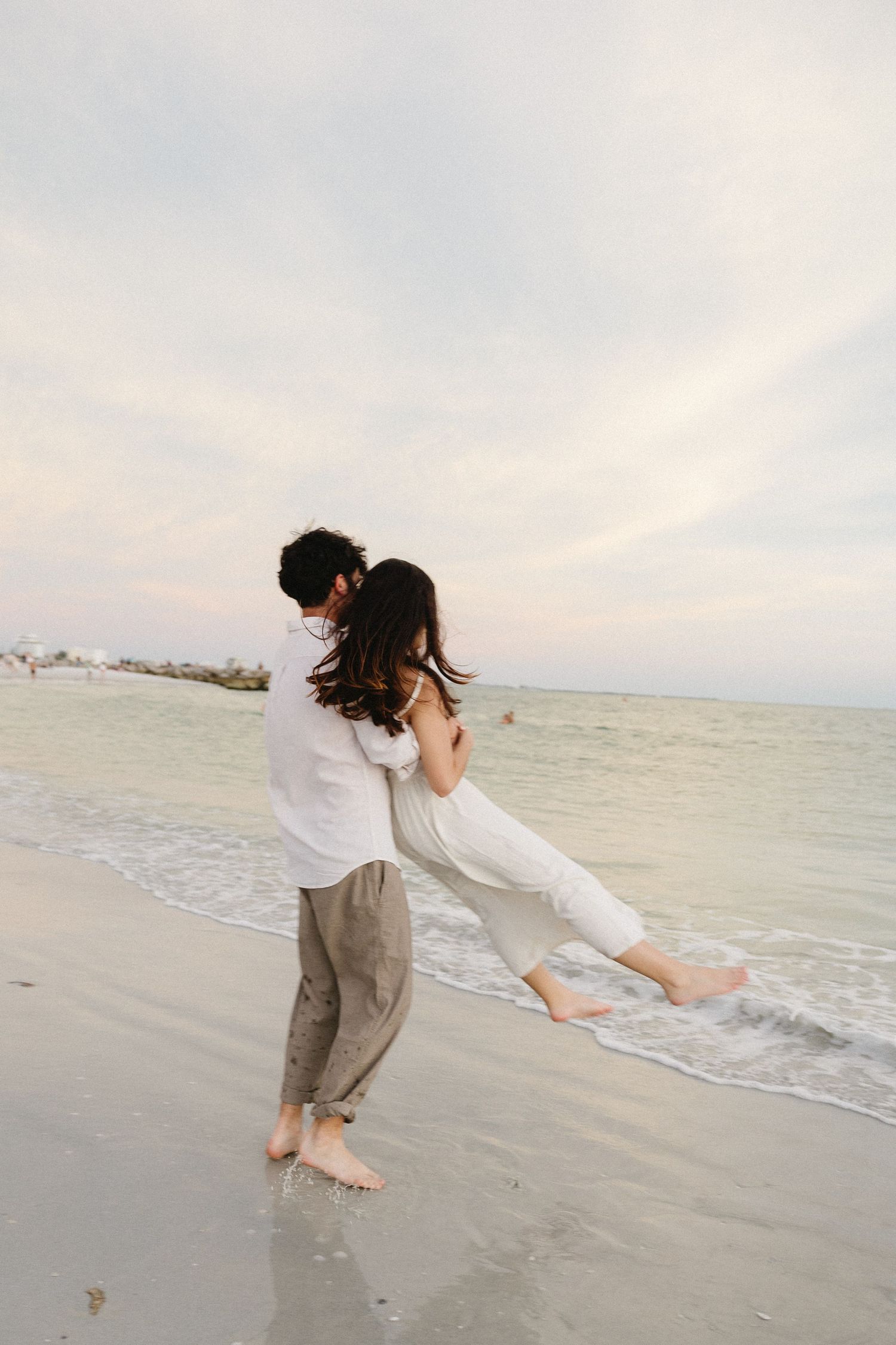 Playful dance sequence on a peaceful beach with gentle waves in the background.