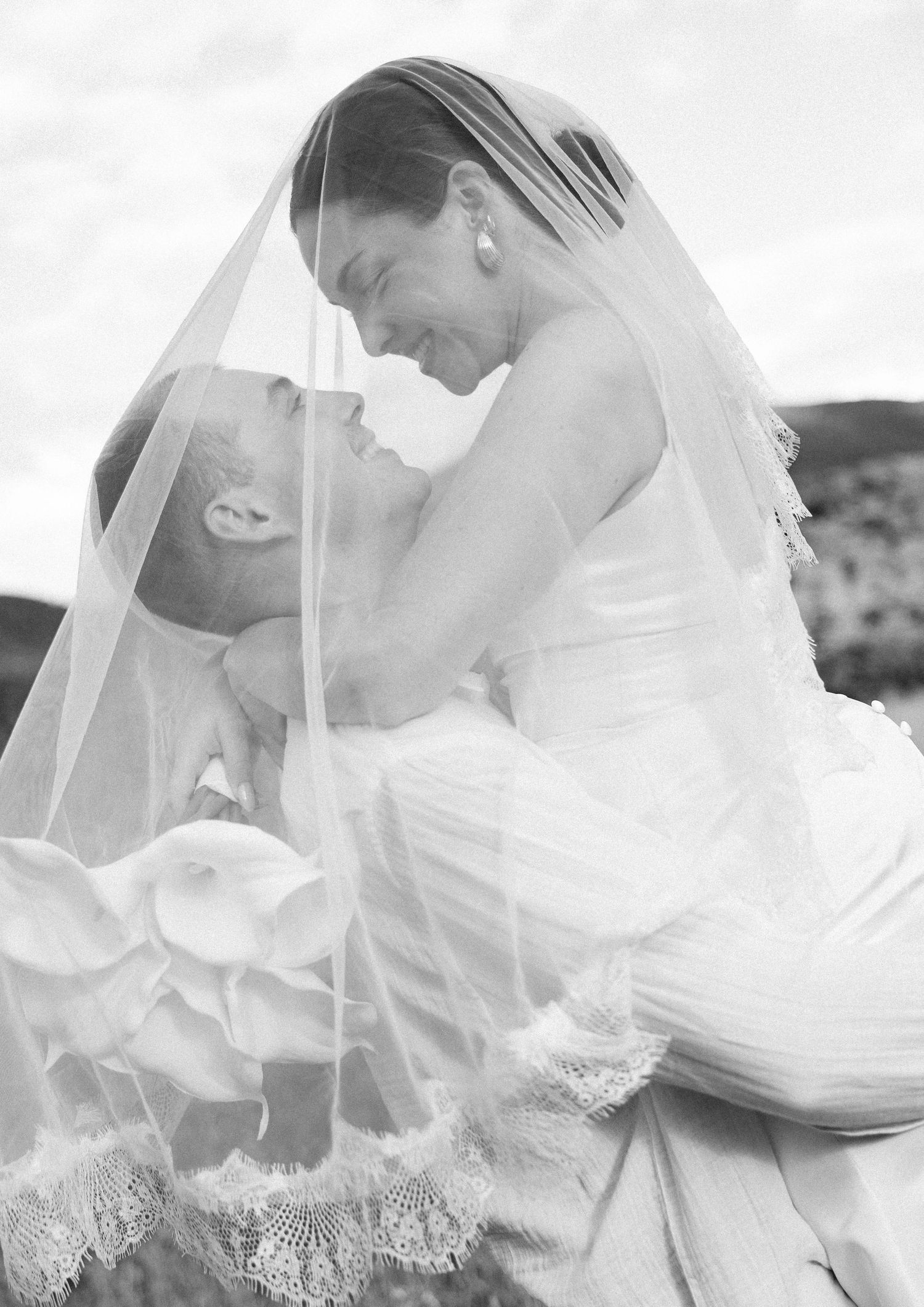 Ethereal black and white portrait of a couple with flowing wedding veil.