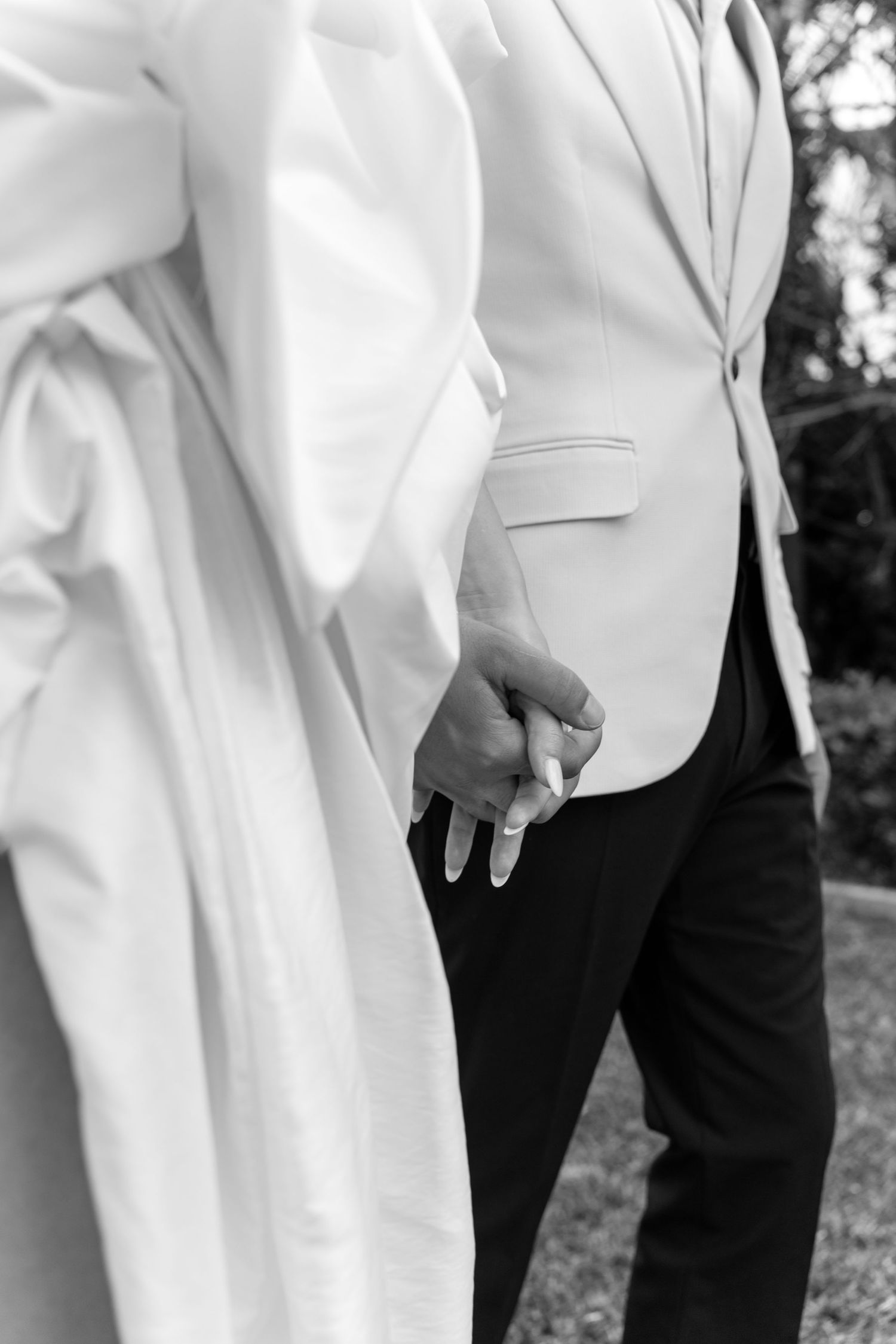 Elegant formal wear detail shots showing white jackets and black trousers at outdoor event.