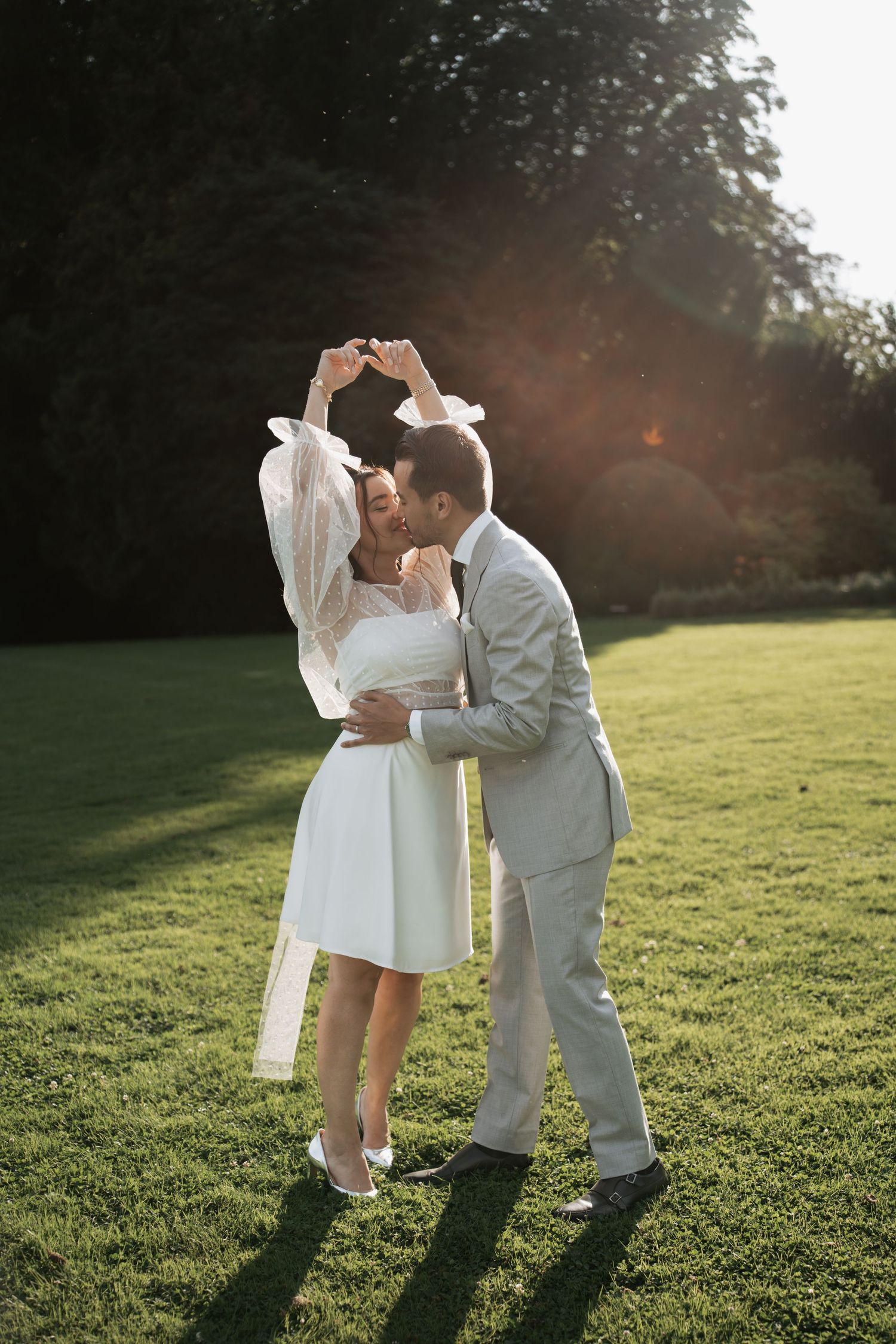 Wedding couple dancing on grassy field during golden hour.