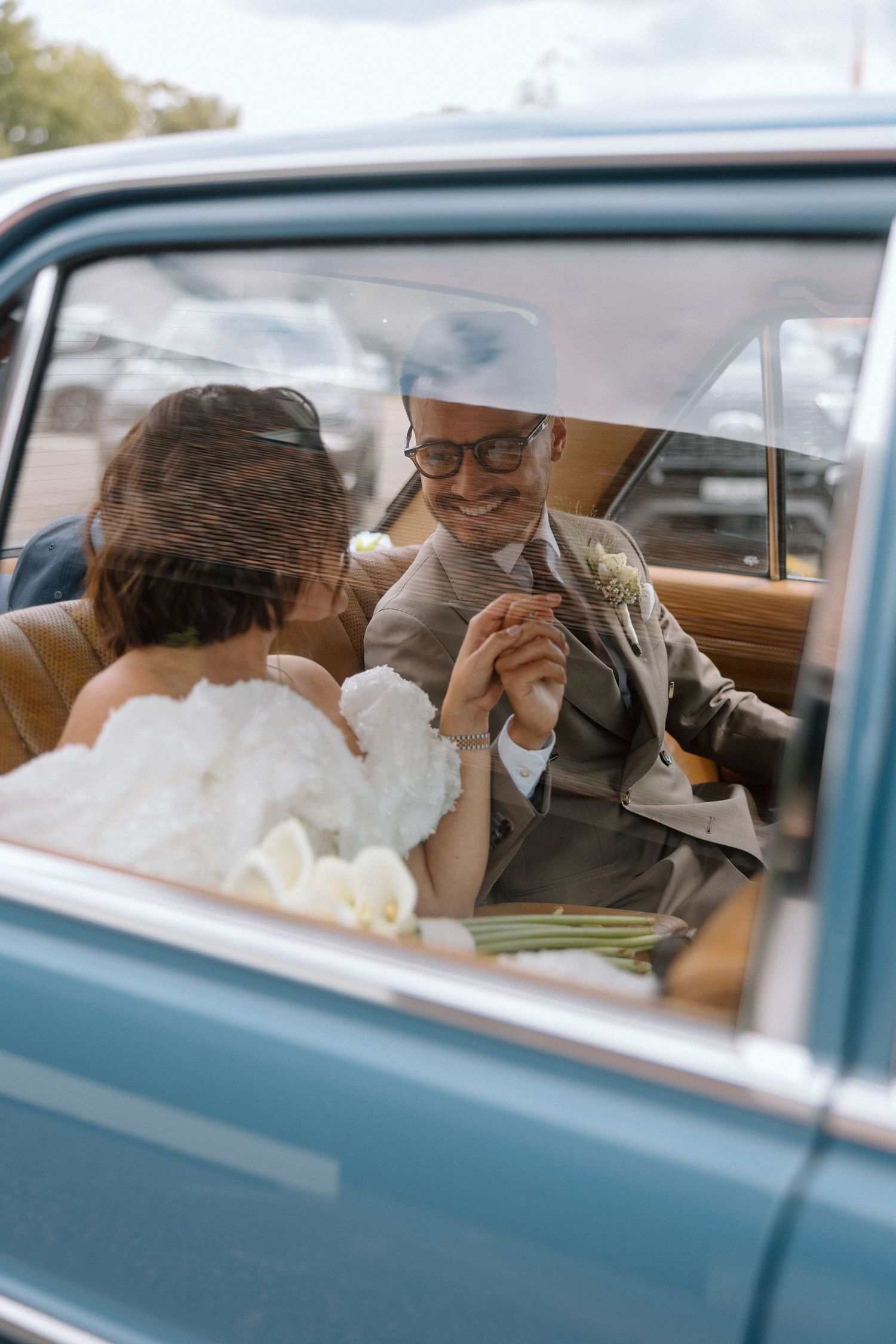Newlyweds share intimate moments inside classic blue vintage car.