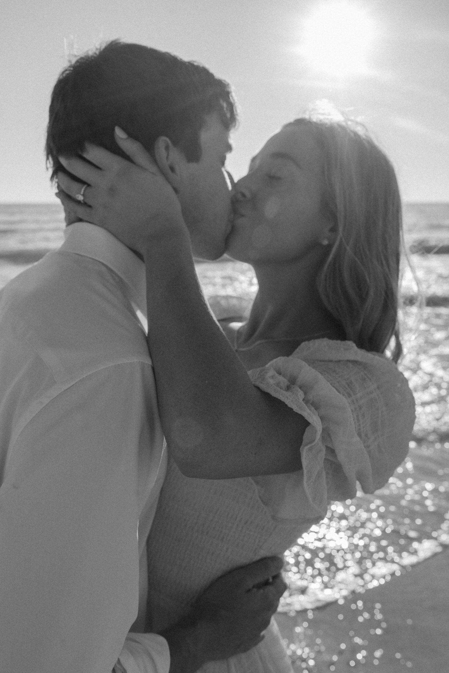 Black and white photos show a romantic couple embracing and kissing on a beach.