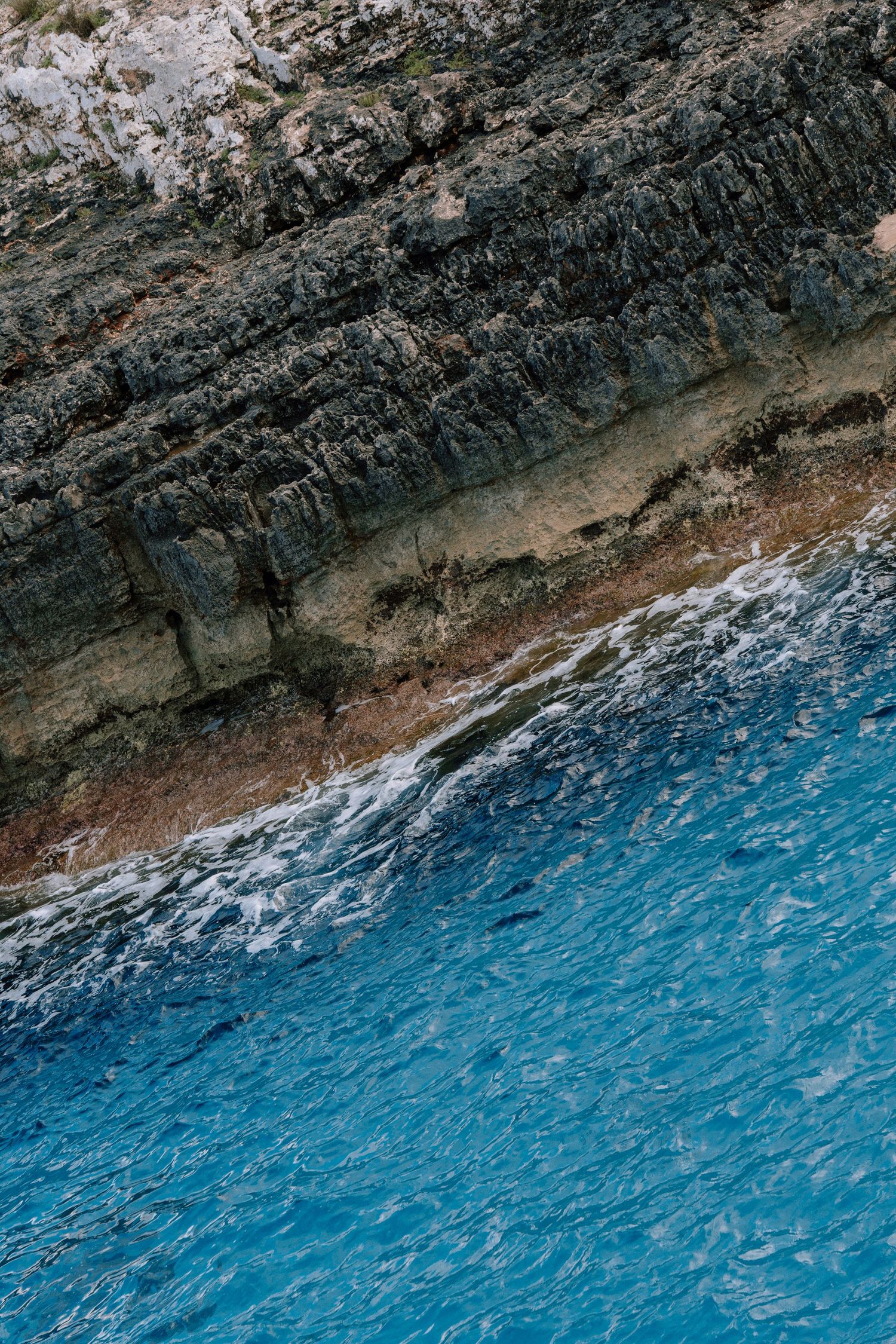 Aerial view of rugged coastline with turquoise blue waters meeting rocky cliffs.