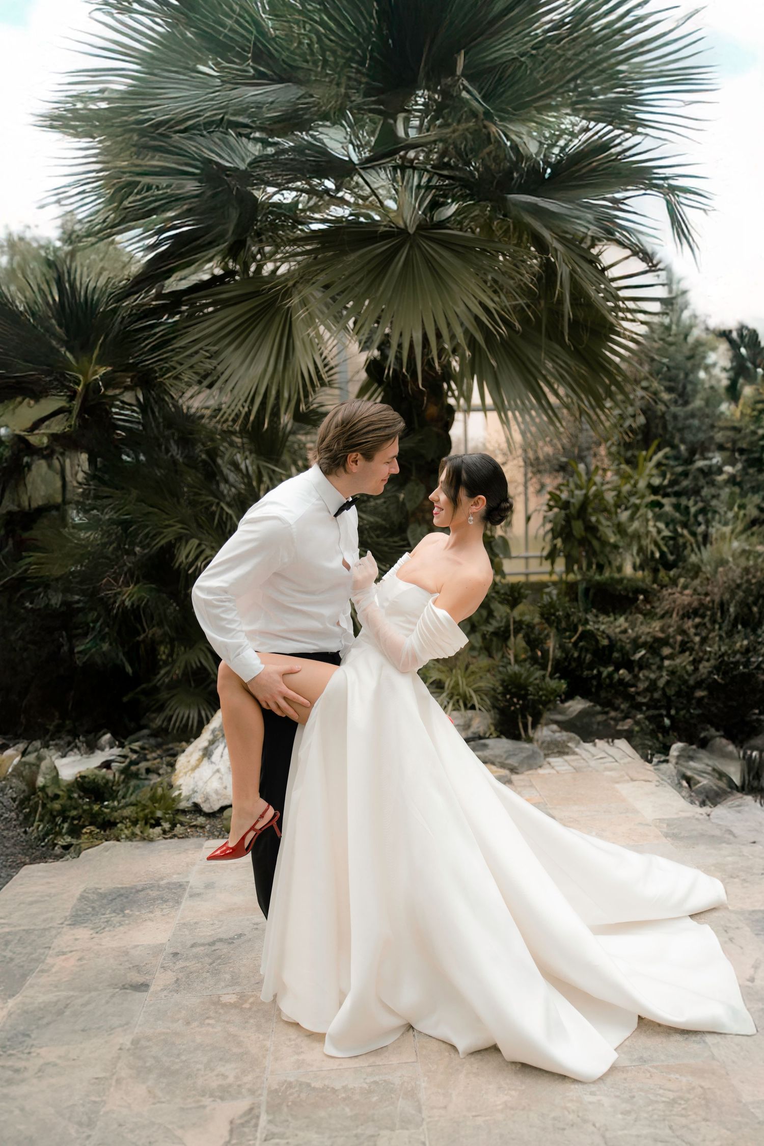 A sequence of dance moves between a couple in formal white attire under palm trees.