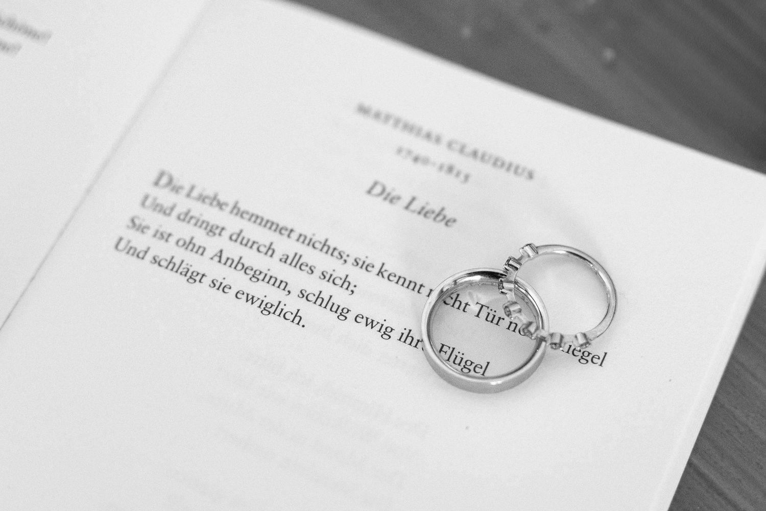 Wedding rings rest on official marriage documents in black and white.
