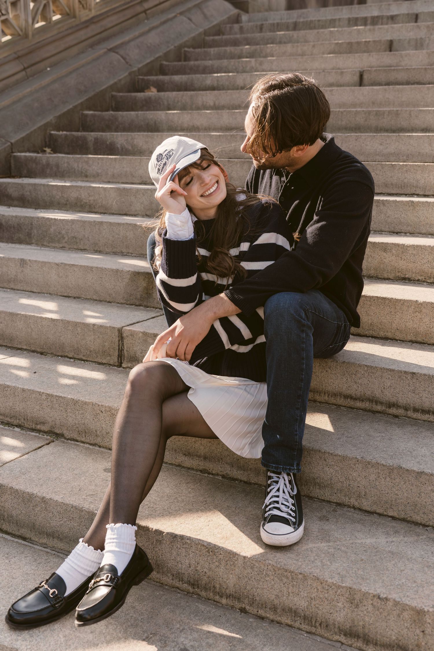 Casual couple sharing playful moments on stone steps in afternoon sunlight.