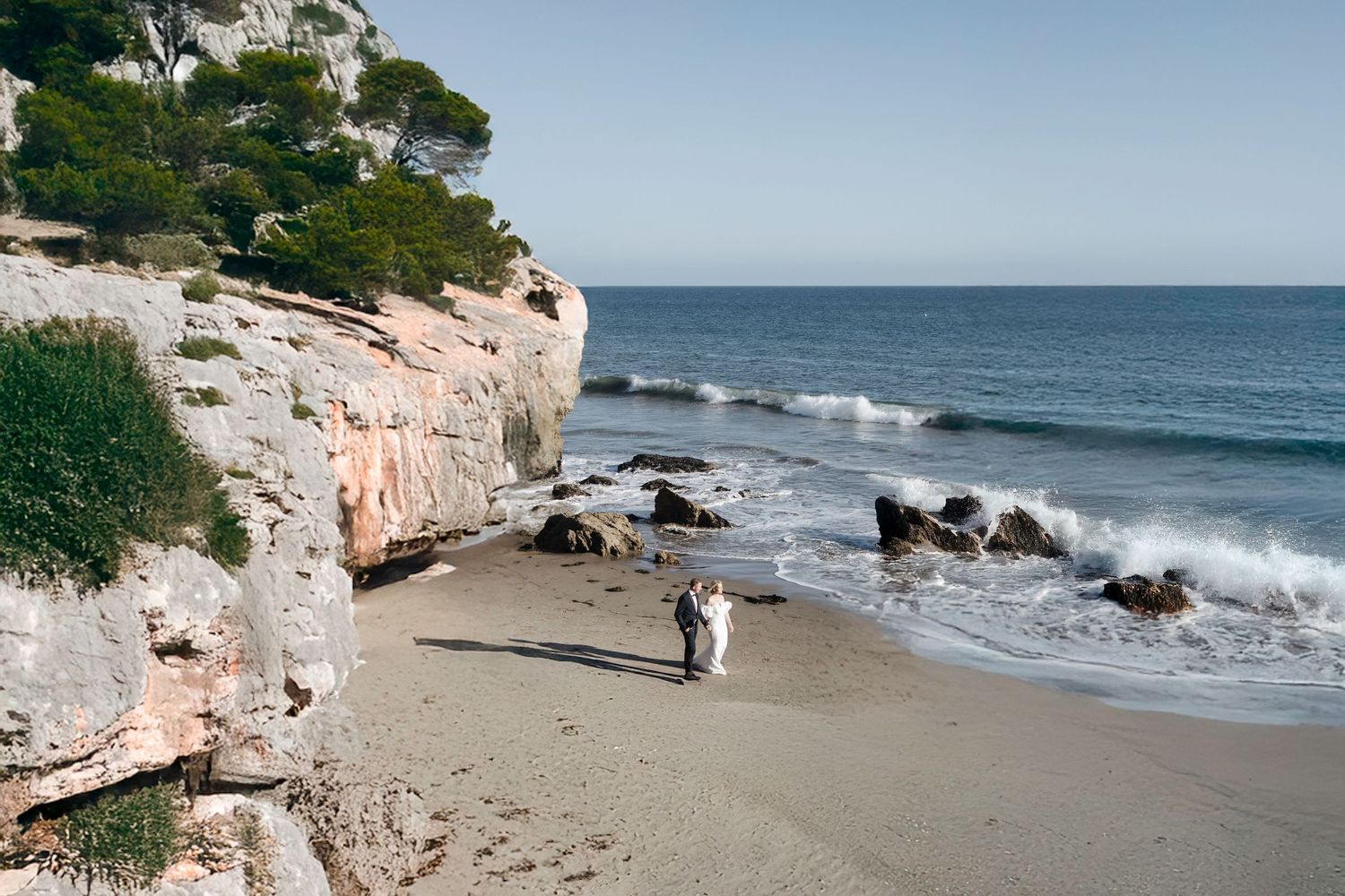 A scenic coastal landscape with rocky cliffs and a sandy beach along the ocean.