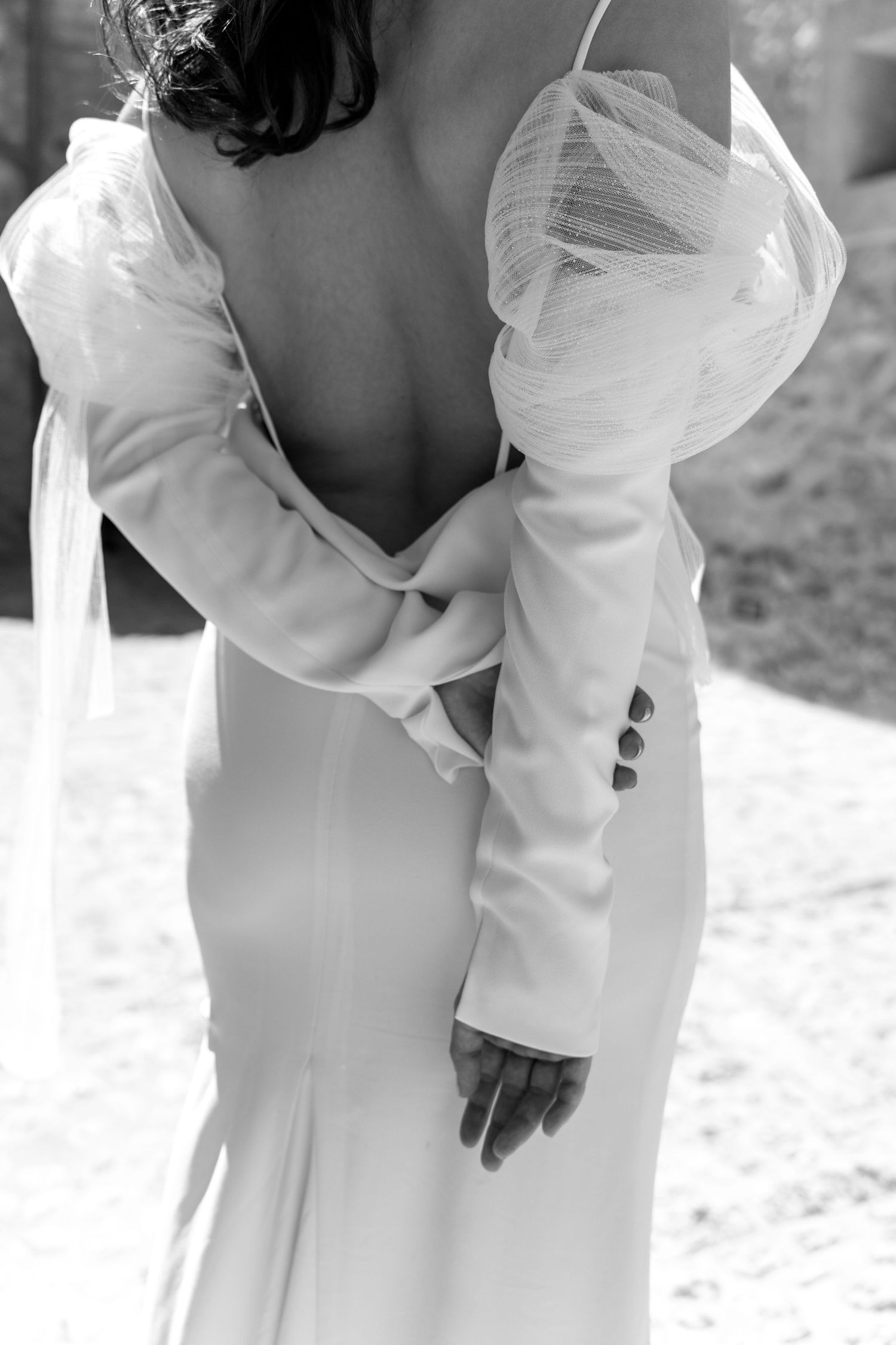 A white wedding dress with delicate buttons and elegant long sleeves shown up close.