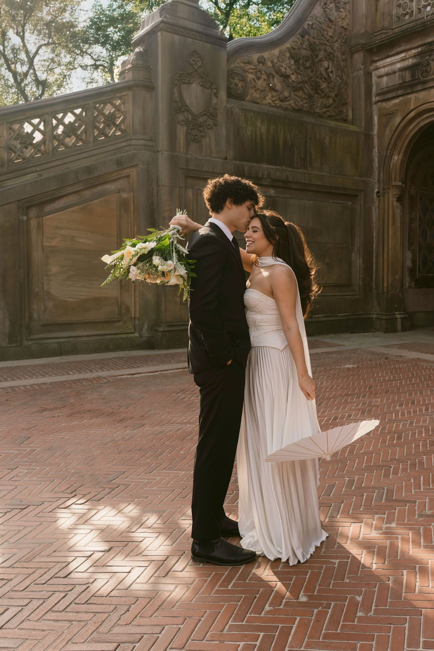 A couple dances gracefully on a brick terrace with architectural columns in the background.