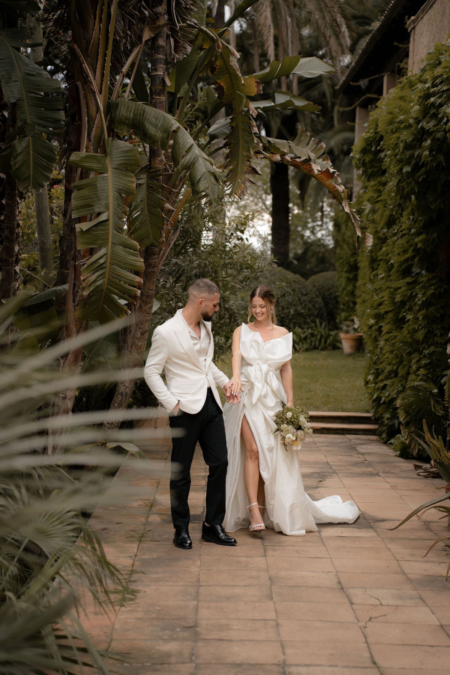 A couple dancing and sharing playful moments on a stone patio surrounded by lush greenery.
