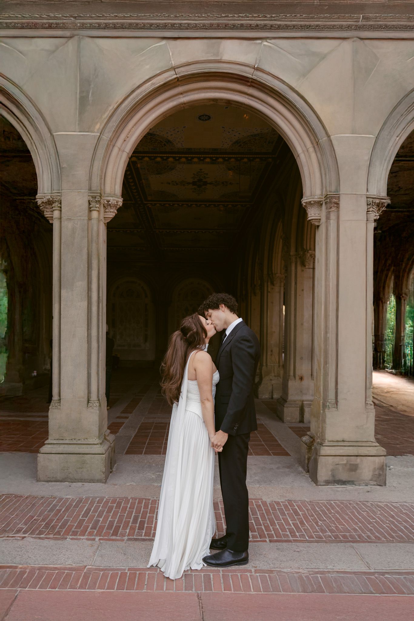 Romantic wedding photos taken under stone archways in classic architecture.