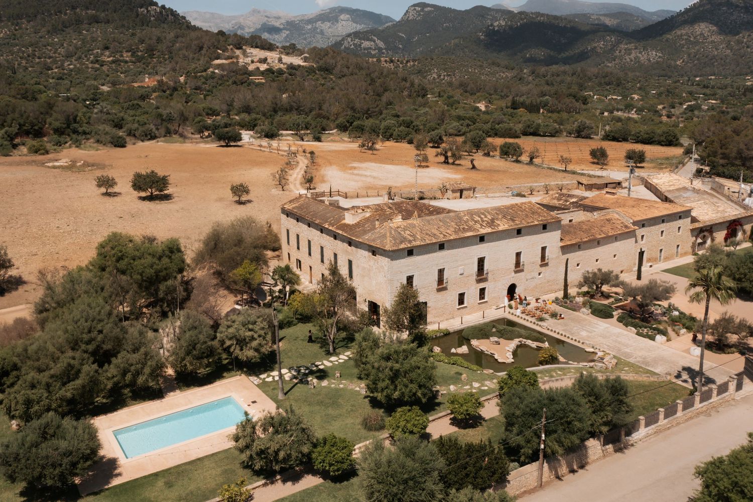 Drone shot of a luxurious Mediterranean estate featuring a swimming pool and landscaped gardens in mountainous terrain.